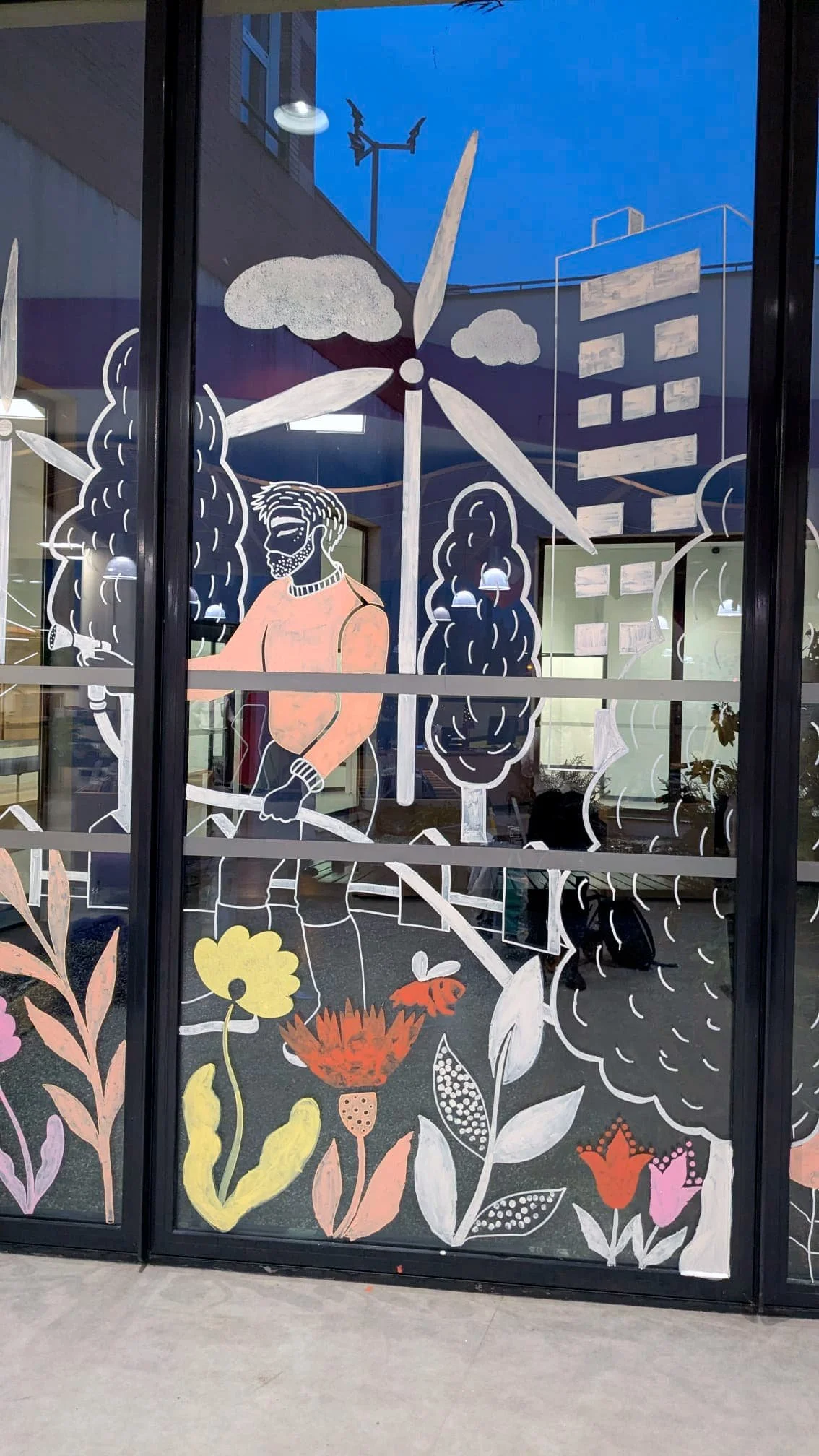 Fresque participative sur les vitrines du patio de la médiathèque des Mureaux, réalisée lors des Nuits de la lecture 2026. Thème "Villes et campagnes" — Panneau centre