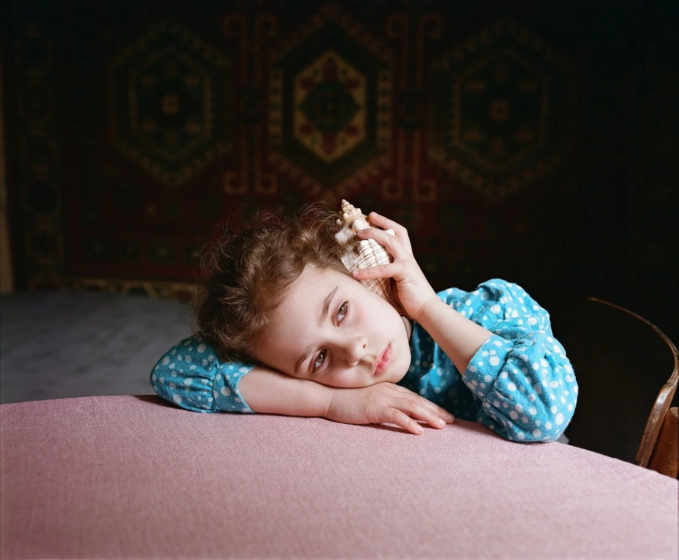 This is my daughter. The seashell acts as a
'conductor'—a link to the distant sea and her ancestors. In many cultures, the shell symbolizes not only journeys but also the voice of the past and memory passed down through time. It is like a 'telephone'