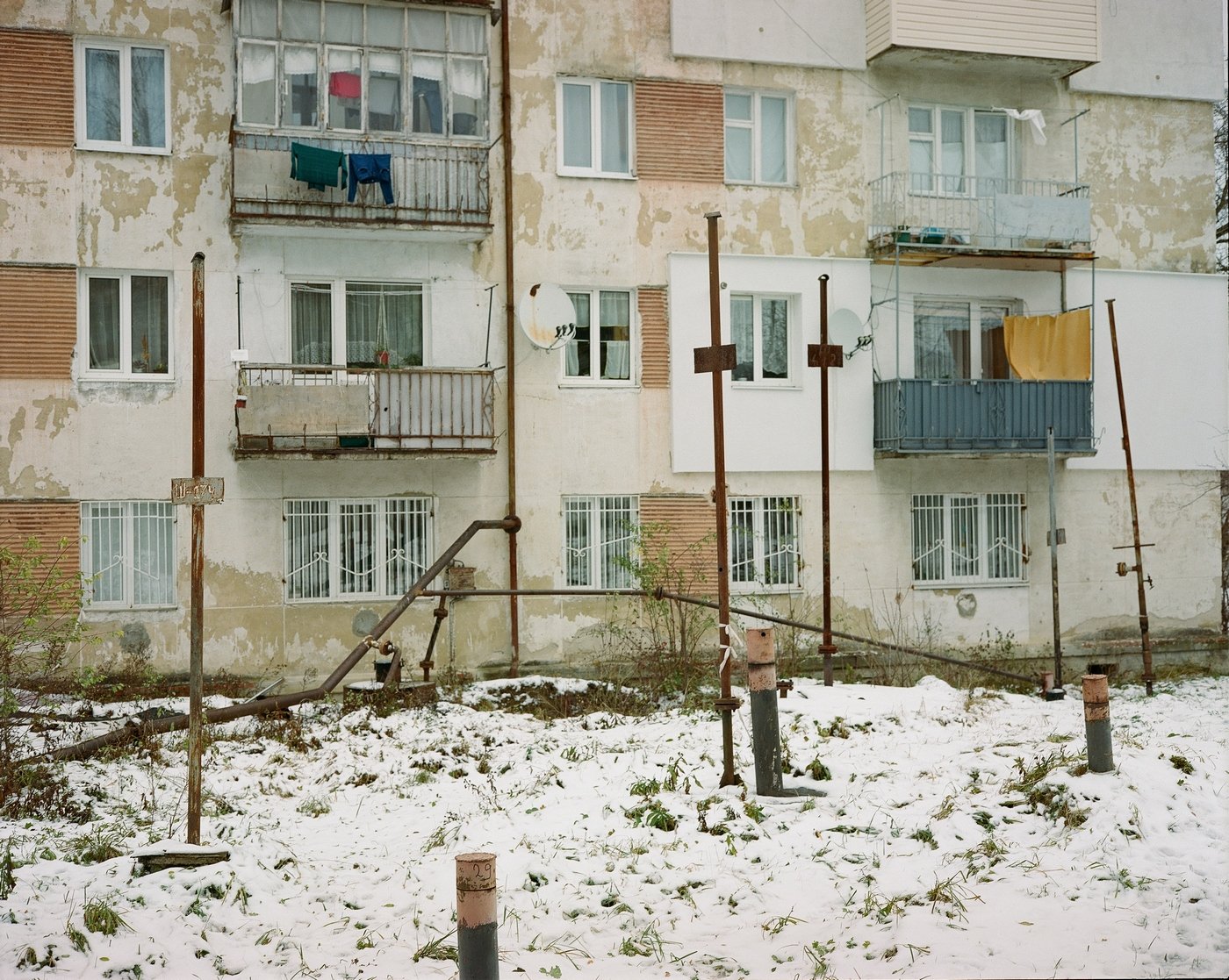 A unique and surreal landscape of a Boryslav
courtyard. In the middle of a snow-covered playground, right beneath the windows of an ordinary apartment building, iron pipes rise from the ground. These are part of a vacuum system designed to vent gas f