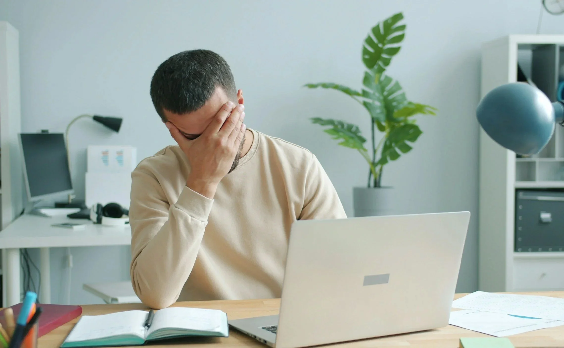 Man sitting at a computer with his head in his hand.
