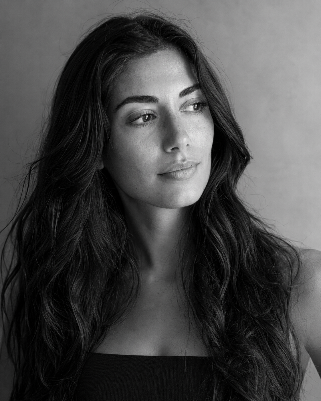 Black and white photo of a woman with long wavy hair looking slightly to the side.