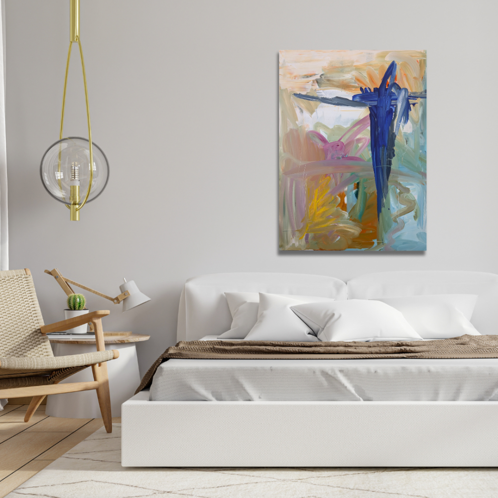 A bedroom with a white bed, abstract colorful artwork on the wall, a wooden chair, a small side table with a cactus, and modern lighting.