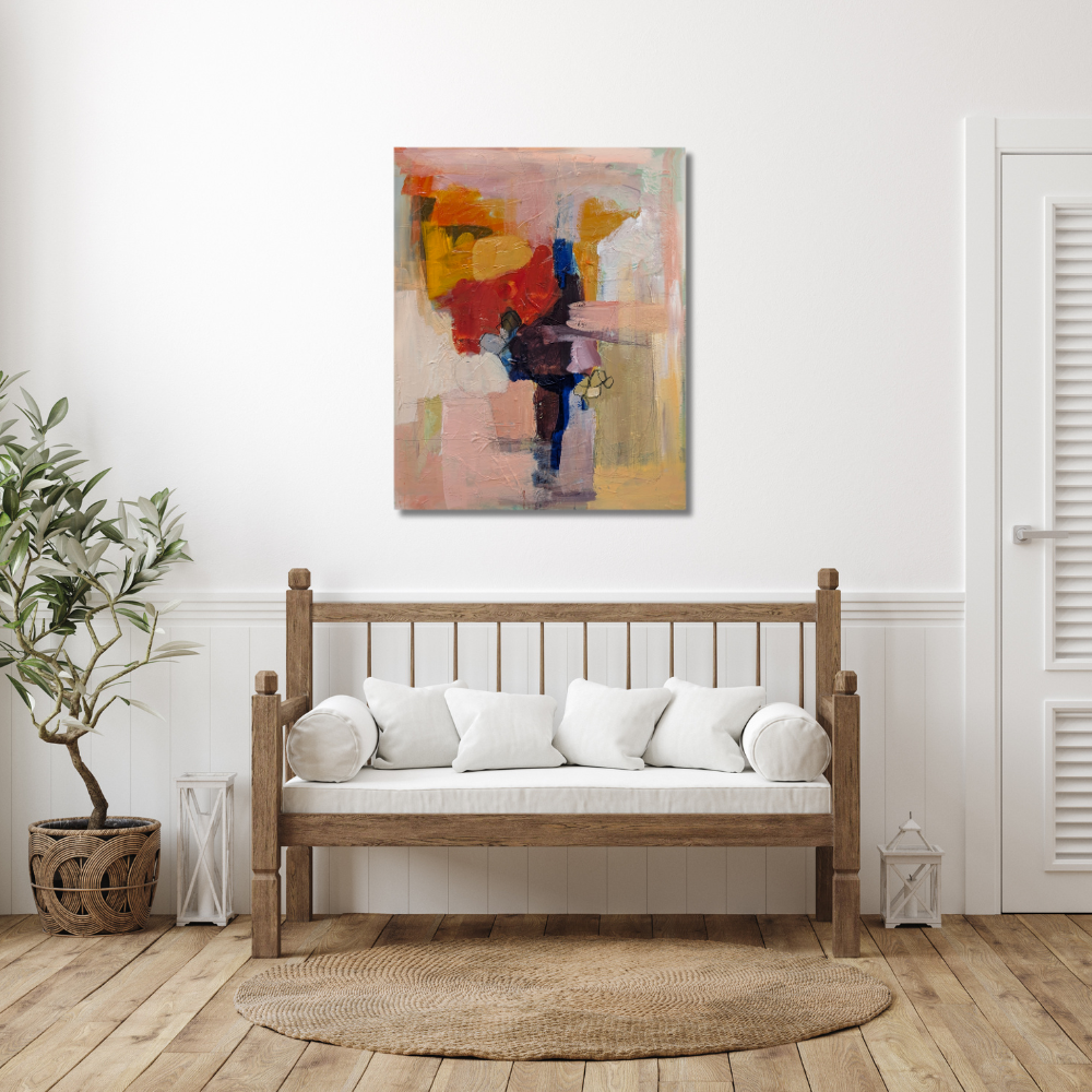 A living room with a wooden sofa adorned with white cushions and pillows, a potted plant on the left, a circular woven rug on the wooden floor, a colorful abstract painting on the white wall above the sofa, and small white lanterns on each side of the sofa.