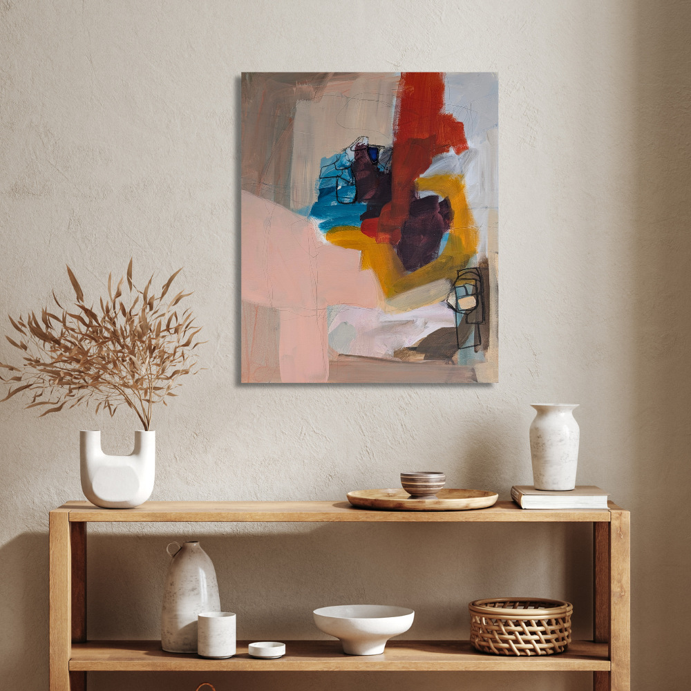 Abstract painting with various colors hanging on a beige wall above a wooden shelf decorated with white and brown vases, bowls, and a wicker basket.