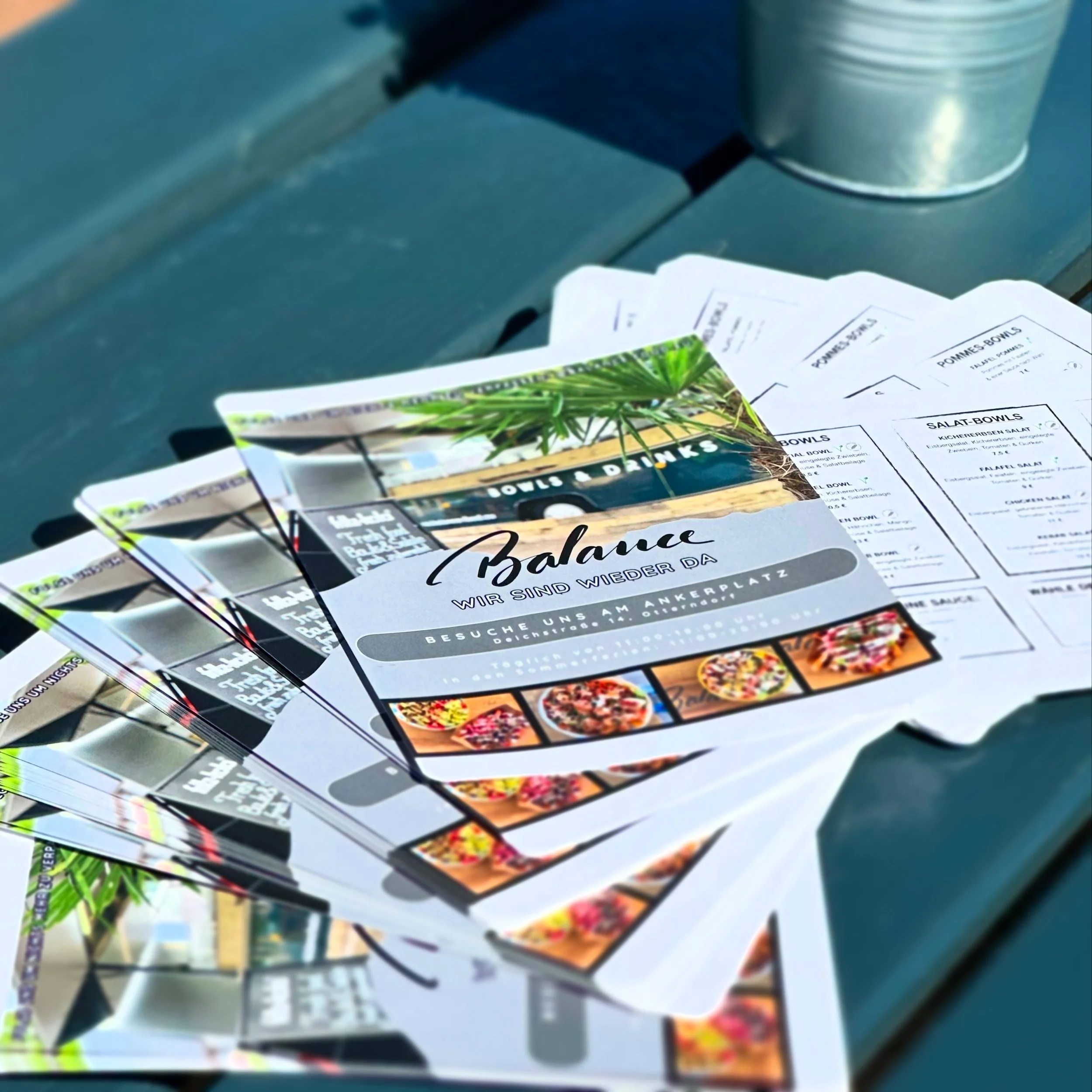 Mehrere Flyer für einen Ort namens Balance, der sich wieder geöffnet hat, und der zum Besuch am Ankerplatz in Otterndorf auffordert. Die Flyer zeigen Bilder von Essen und Drinks.