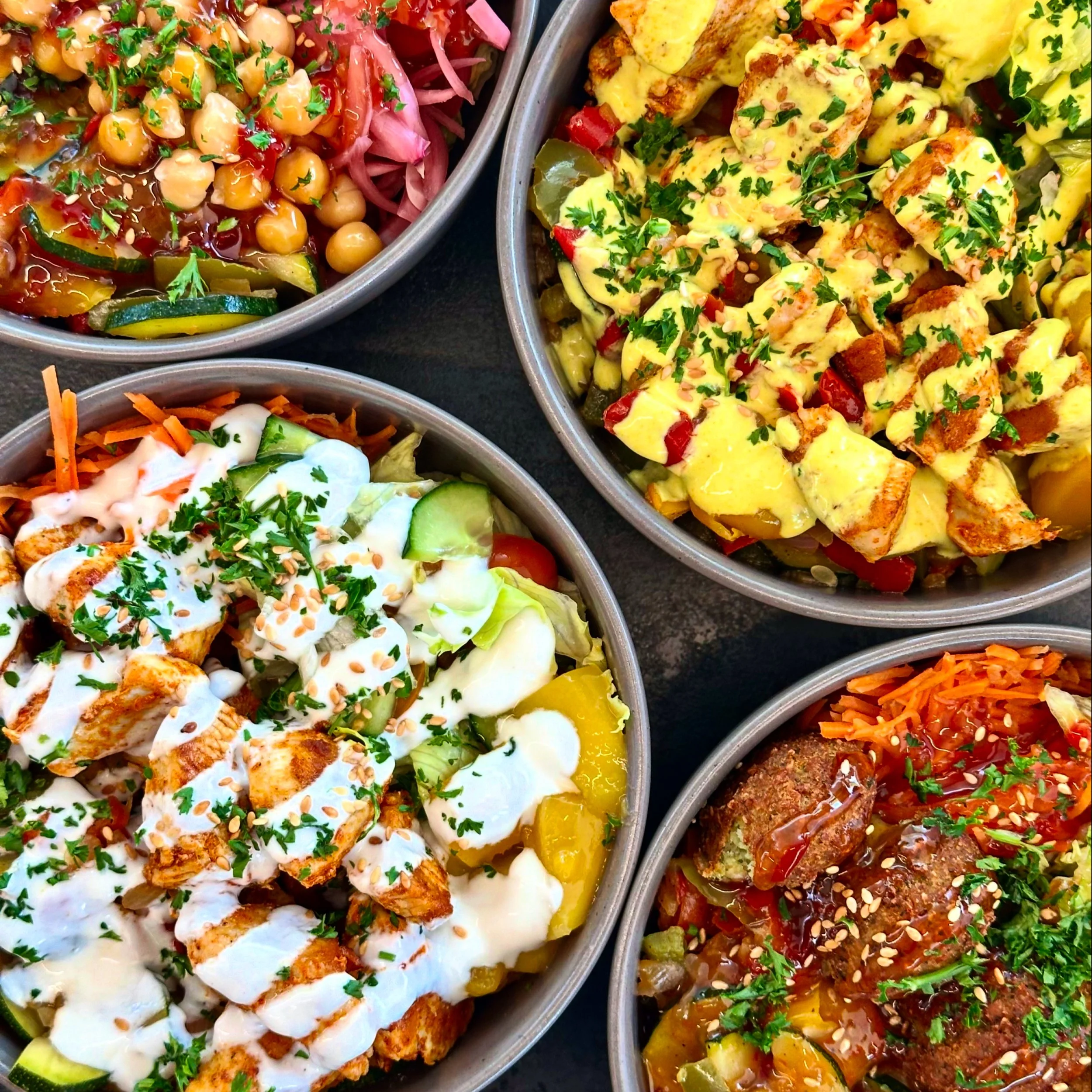 Verschiedene bunte Salate und Gerichte in Bowls, mit frischen Kräutern und Saucen.