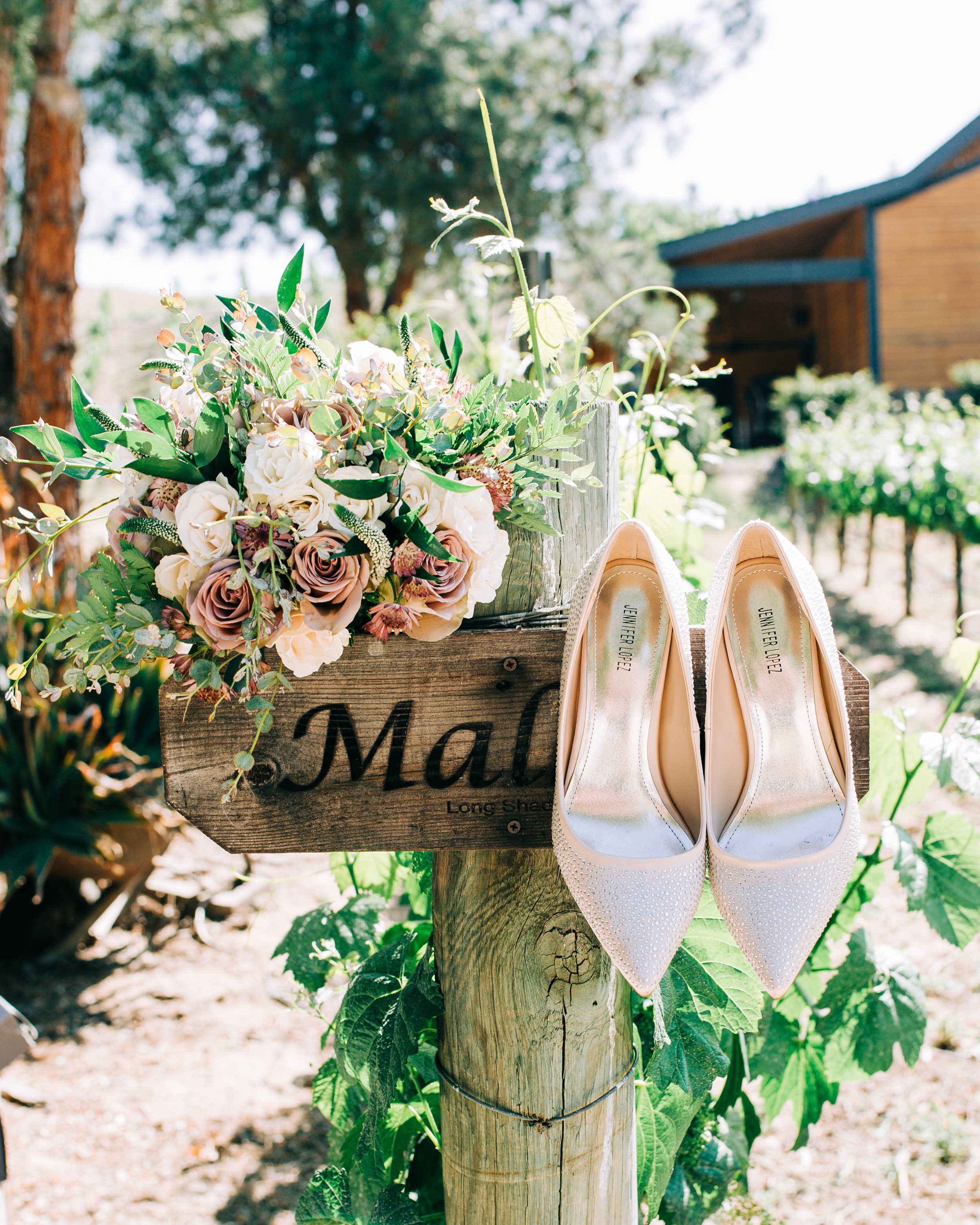 Bride's high heel shoes and rose floral bouquet on a vineyard.jpg