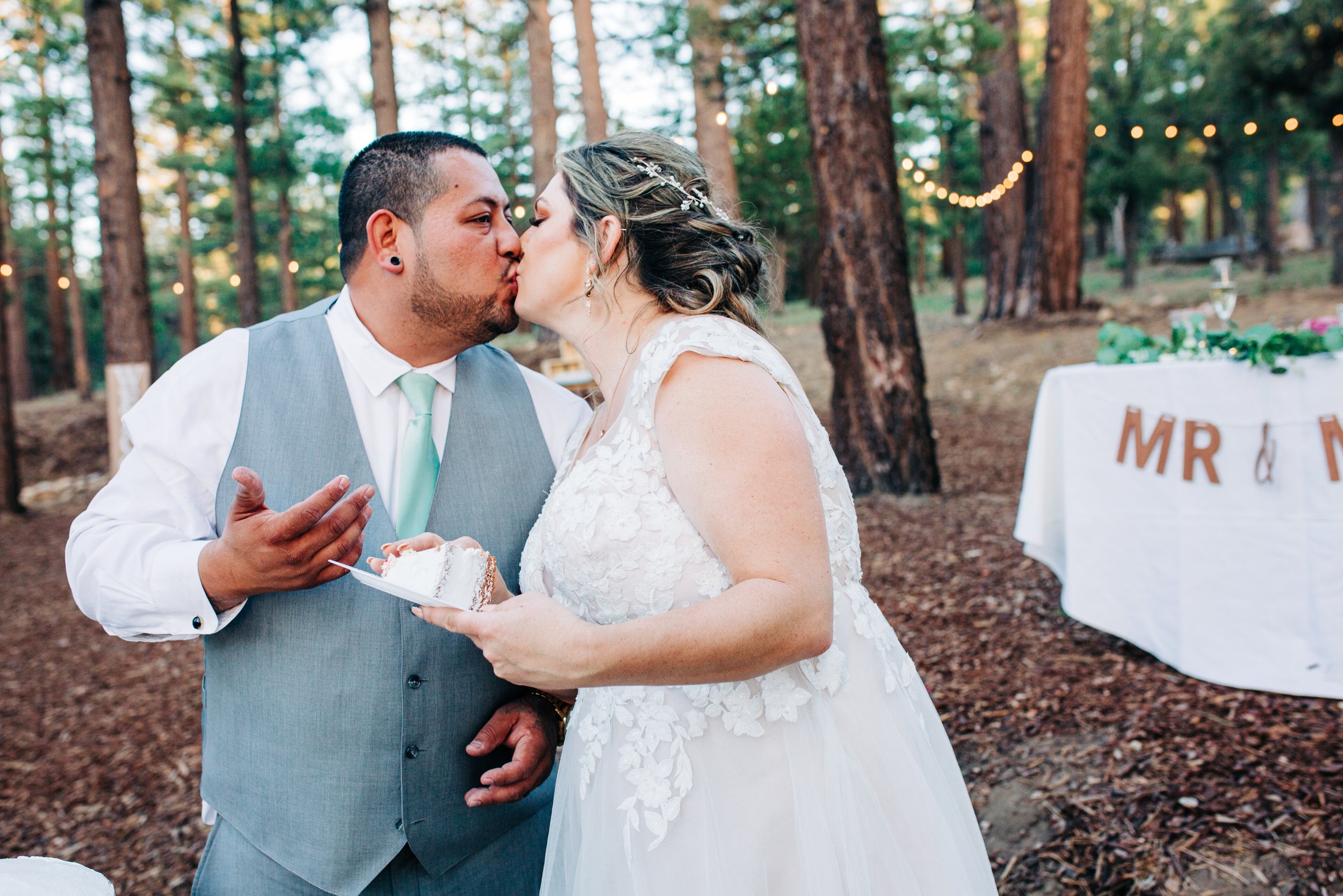 bride and groom feeding wedding cake and kissing.jpg