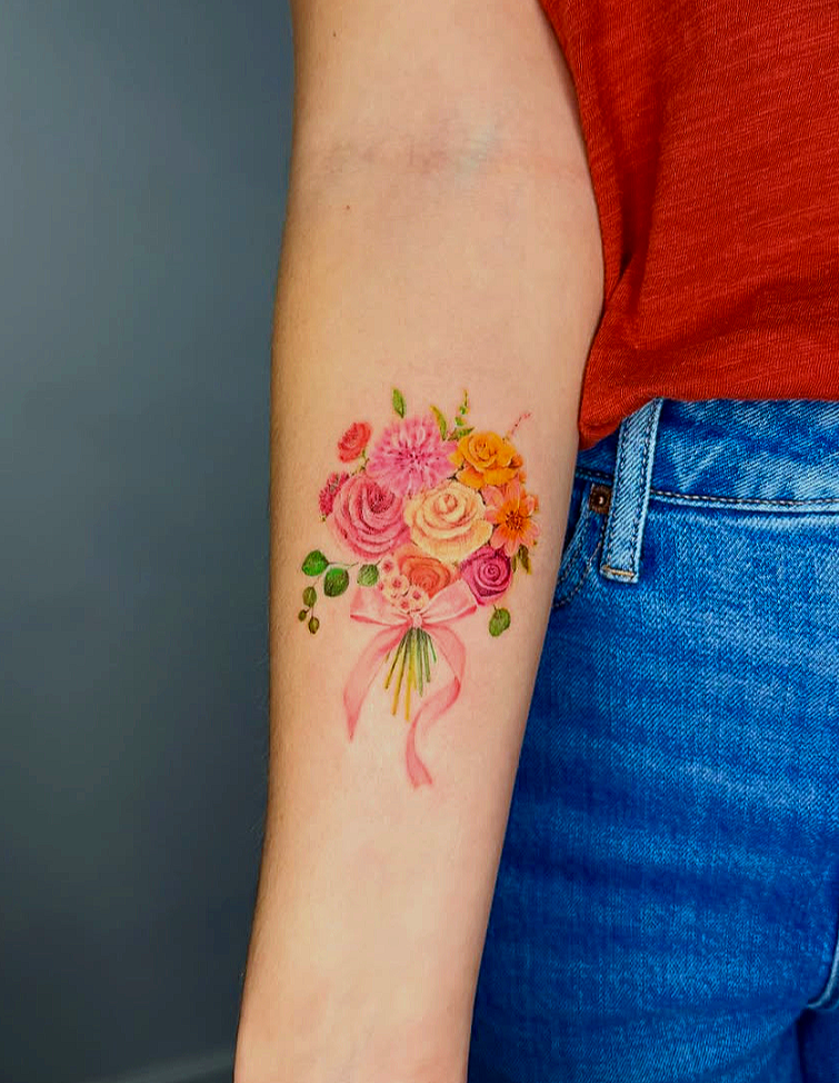 Tattoo of flowers, including a rose, lilies, and bees on an arm.
