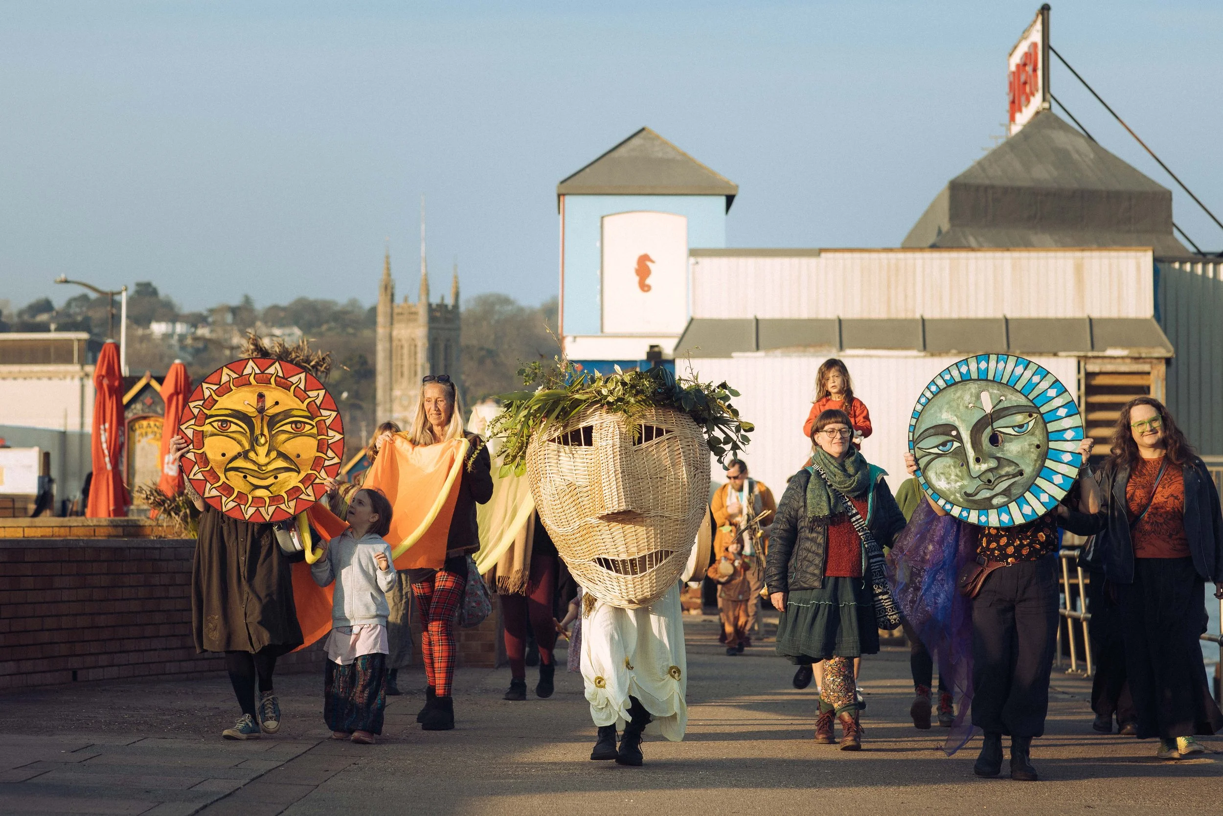 Members of the Teignmouth Folk Preservation Society parade along the promenade as part of the Spring Solstice ritual. Member Amerie wears the giant wicker head constructed by basket artist Lewis Prosser.