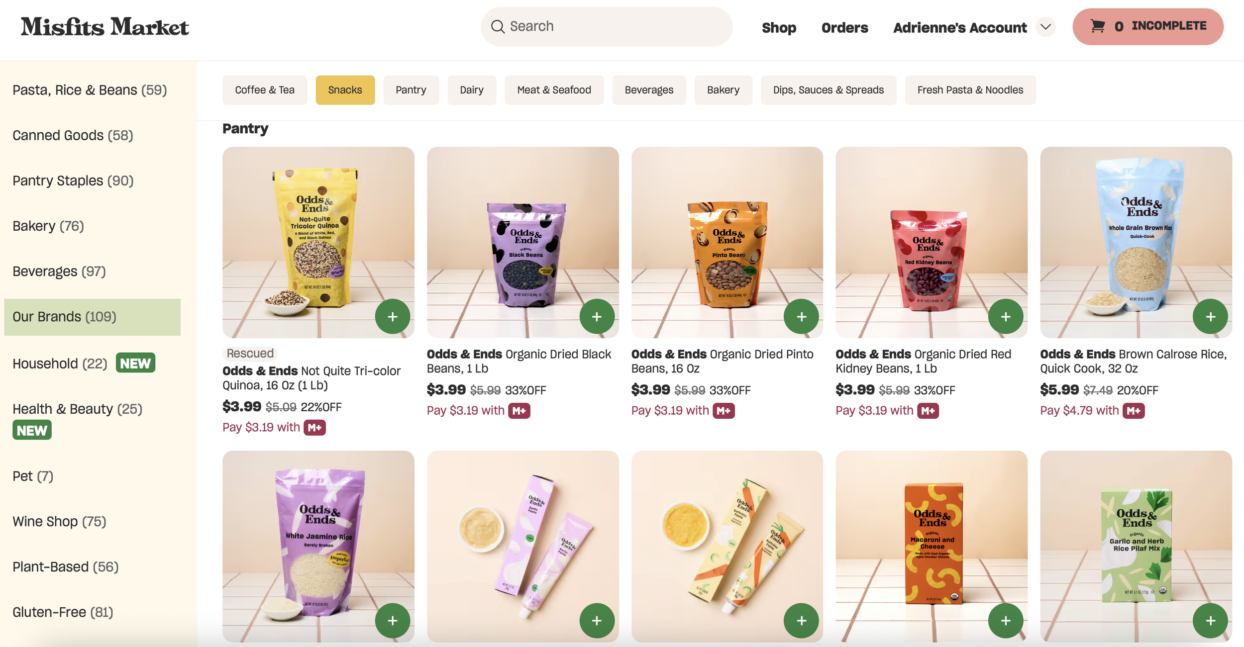 Screenshot of an online grocery store called 'Misfits Market,' specifically the 'Snacks' section under the 'Our Brands' category. Shows various packaging of Odds & Ends organic dried beans and rice, including black beans, pinto beans, red kidney beans, and brown rice, with prices and discounts listed.