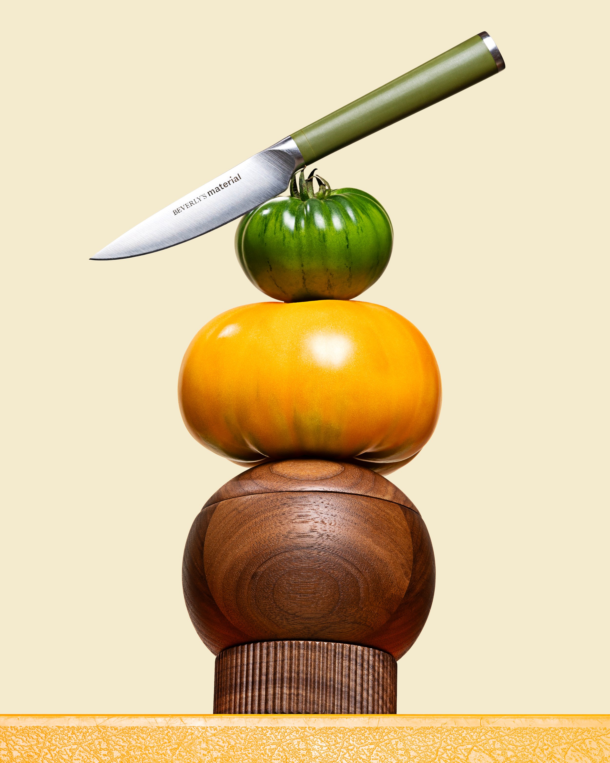 Stacked tomatoes with a kitchen knife balanced on the top tomato.