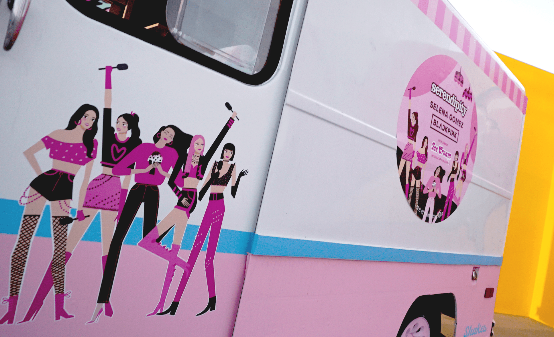An ice cream truck with cartoon illustrations of the girl group Blackpink on the side, featuring five women in pink and black outfits striking various poses. There's also a round sticker on the truck with similar paraphernalia and the group's names.