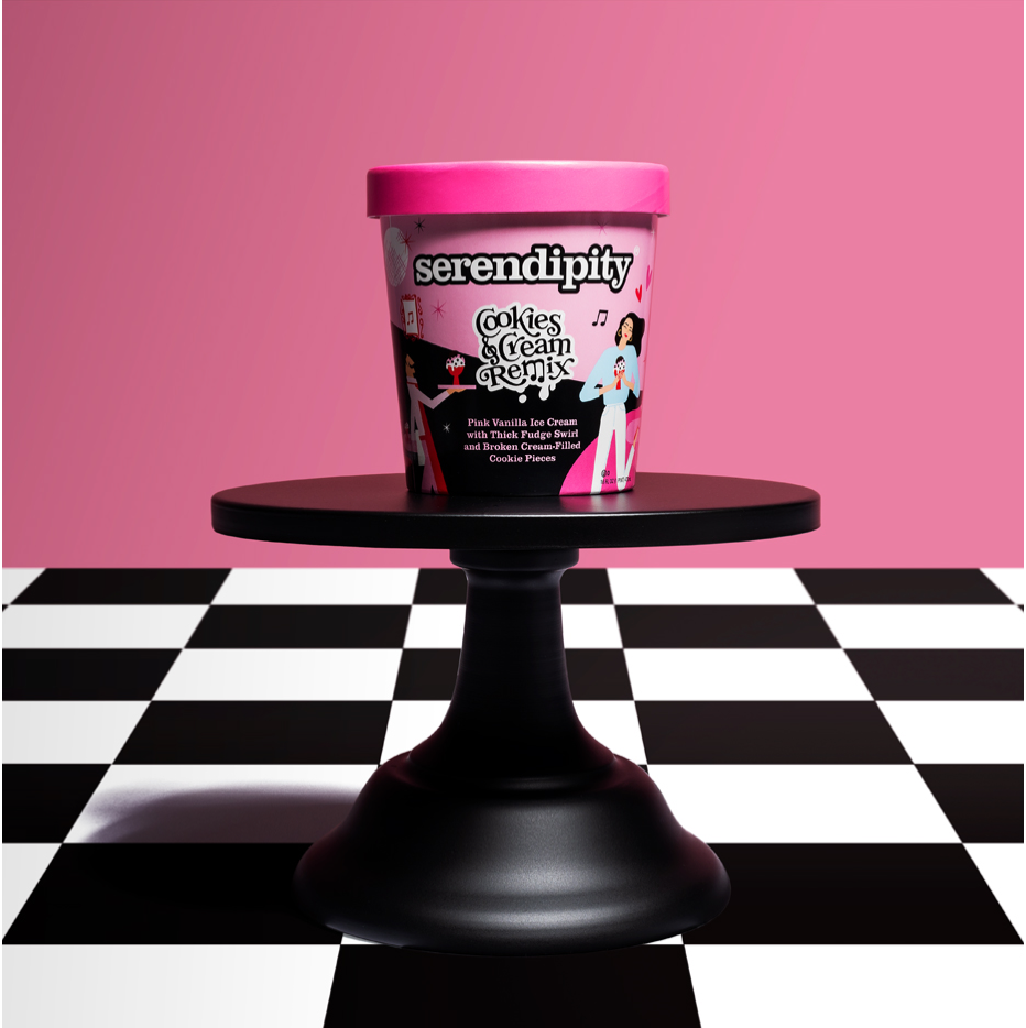 A pink container of Serendipity Cookies & Cream Remix ice cream on a black pedestal stand, with a pink background and a black-and-white checkered floor.