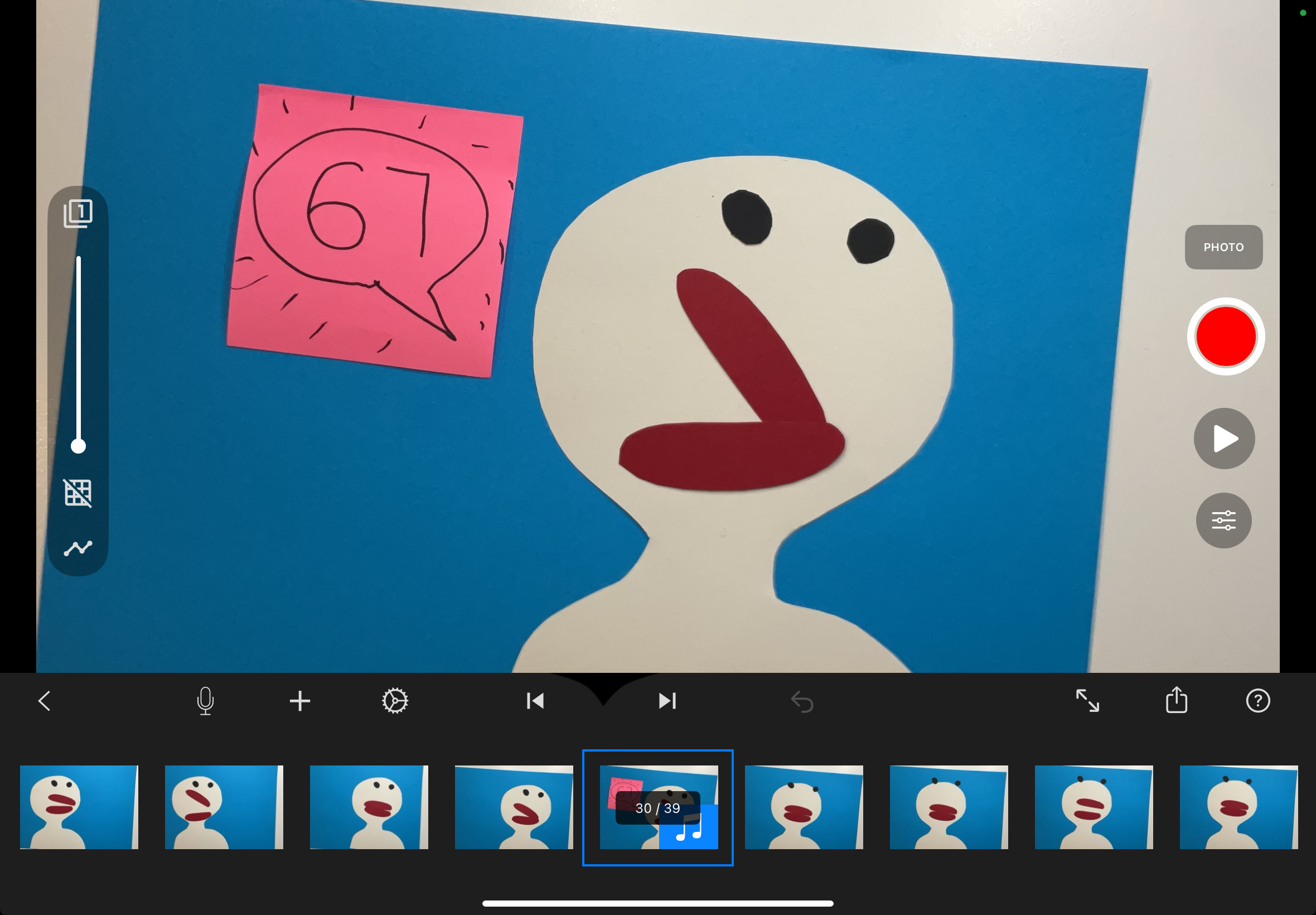 Paper cut-out stop motion scene with a white cartoon character and pink square on a blue background.