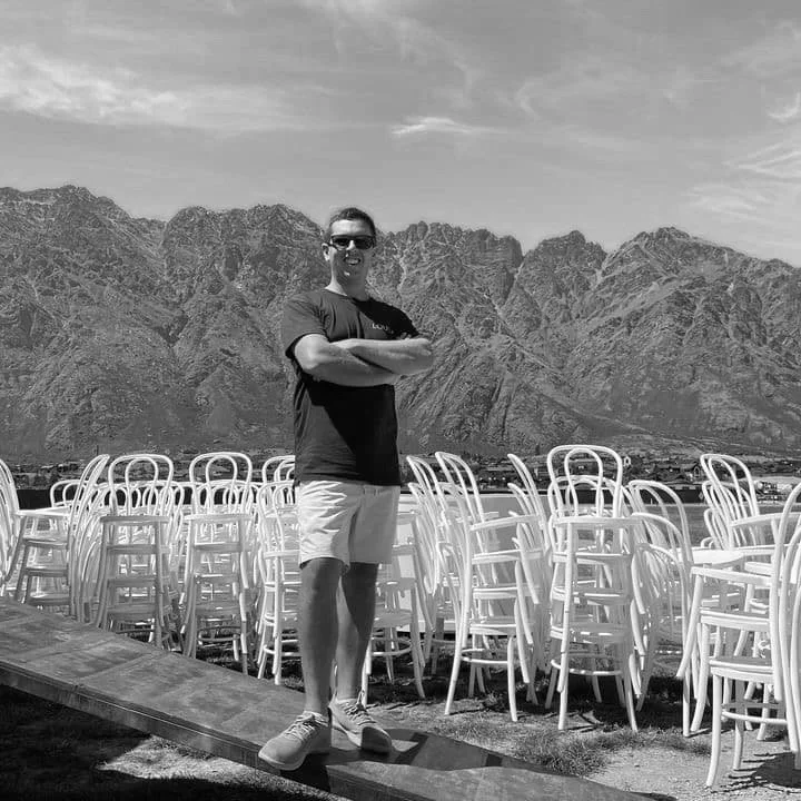 James, founder of Loula Event Hire, with stacked white Bentwood chairs