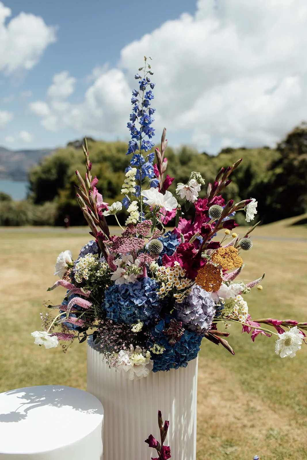Floral arrangement on a white plinth at Pete & Kelsie's wedding at Mt Vernon Lodge, Akaroa