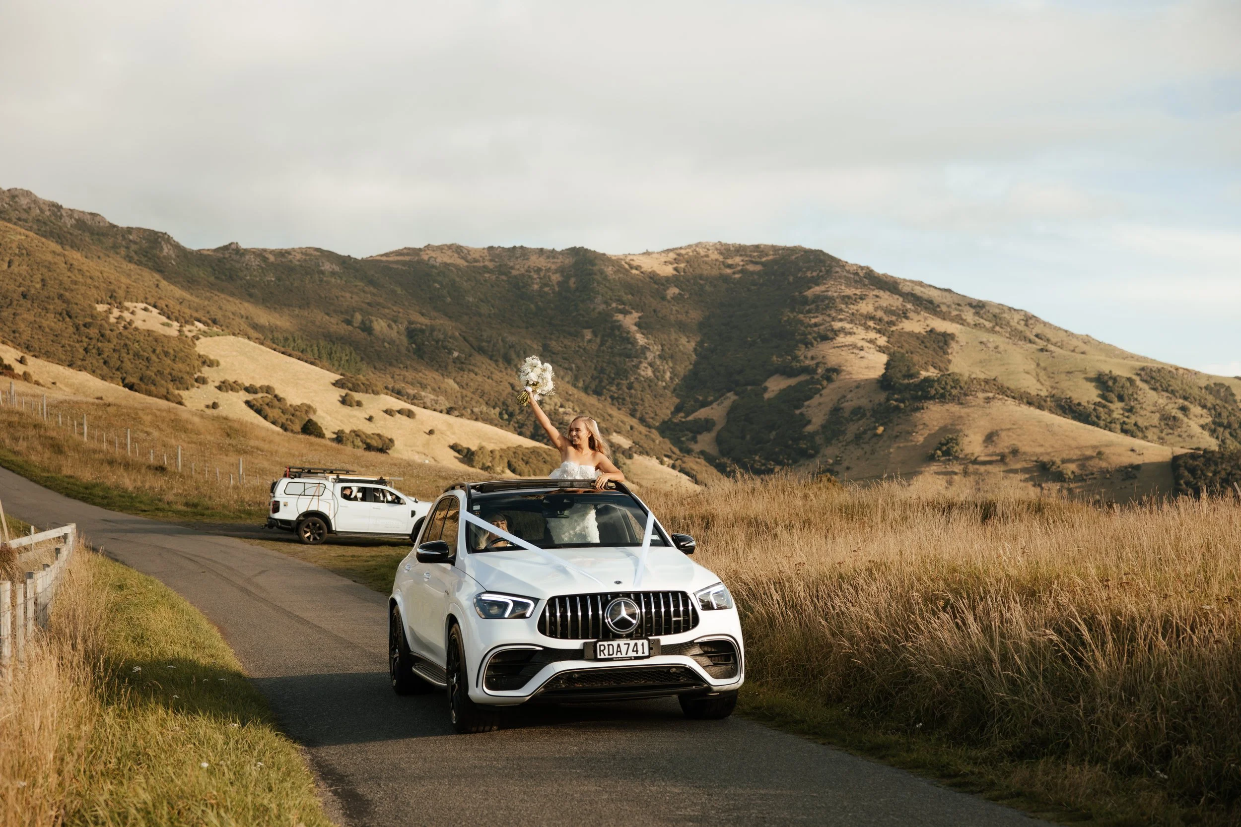 Wedding car on the road over the Akaroa hills at Grace & Callum's wedding in Akaroa