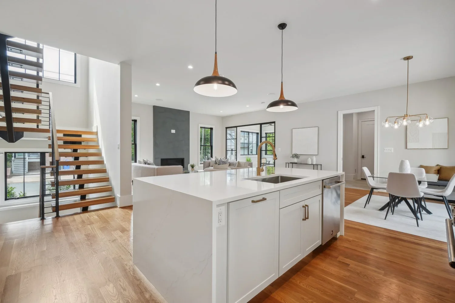 Open-concept kitchen with white island, brass fixtures, and floating staircase in Arlington, VA