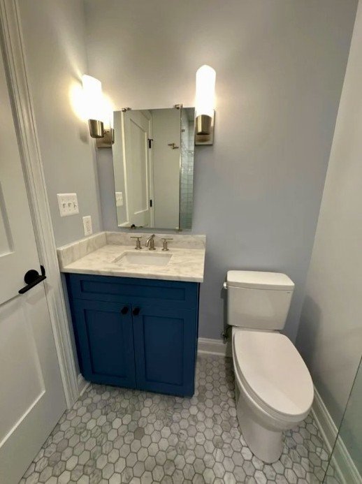 Bathroom with custom vanity, wall sconces, and marble floor tile in Old Town Alexandria