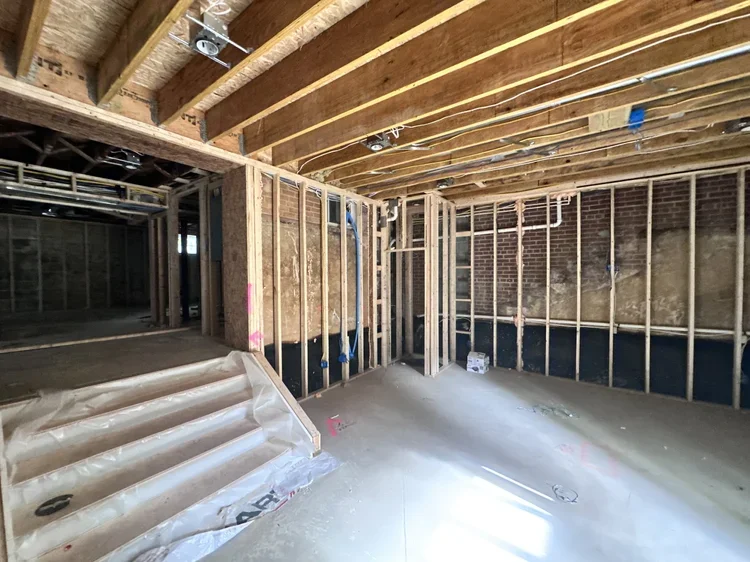 Basement framing showing exposed floor joists, wall studs, and rough plumbing during construction