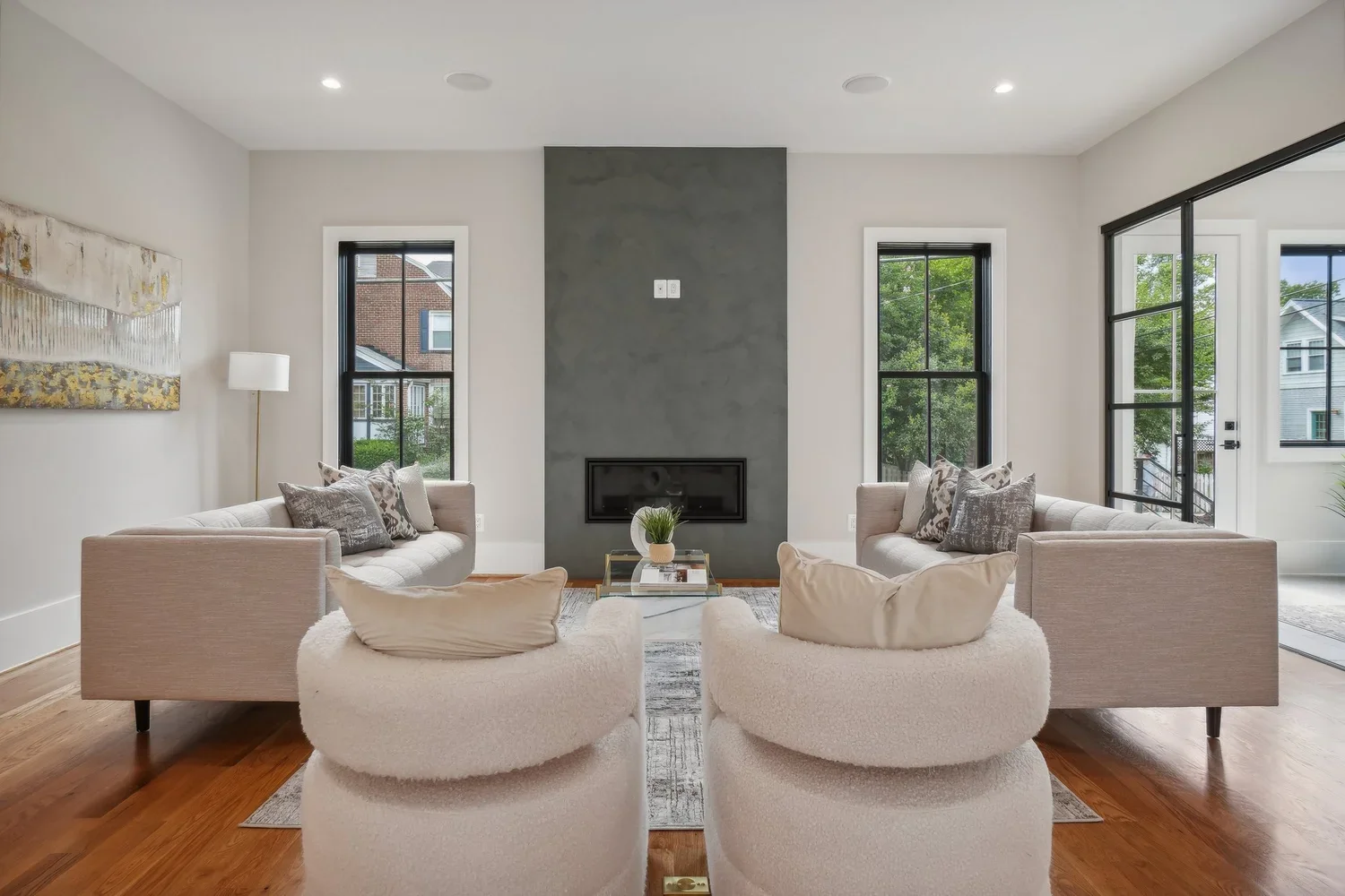 Living room with plaster fireplace surround, sectional sofas, and black-framed windows in Arlington, VA