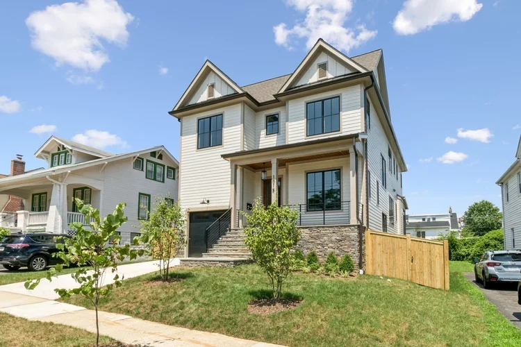 Custom home exterior with white siding, black trim, and stone accent wall in Arlington, VA