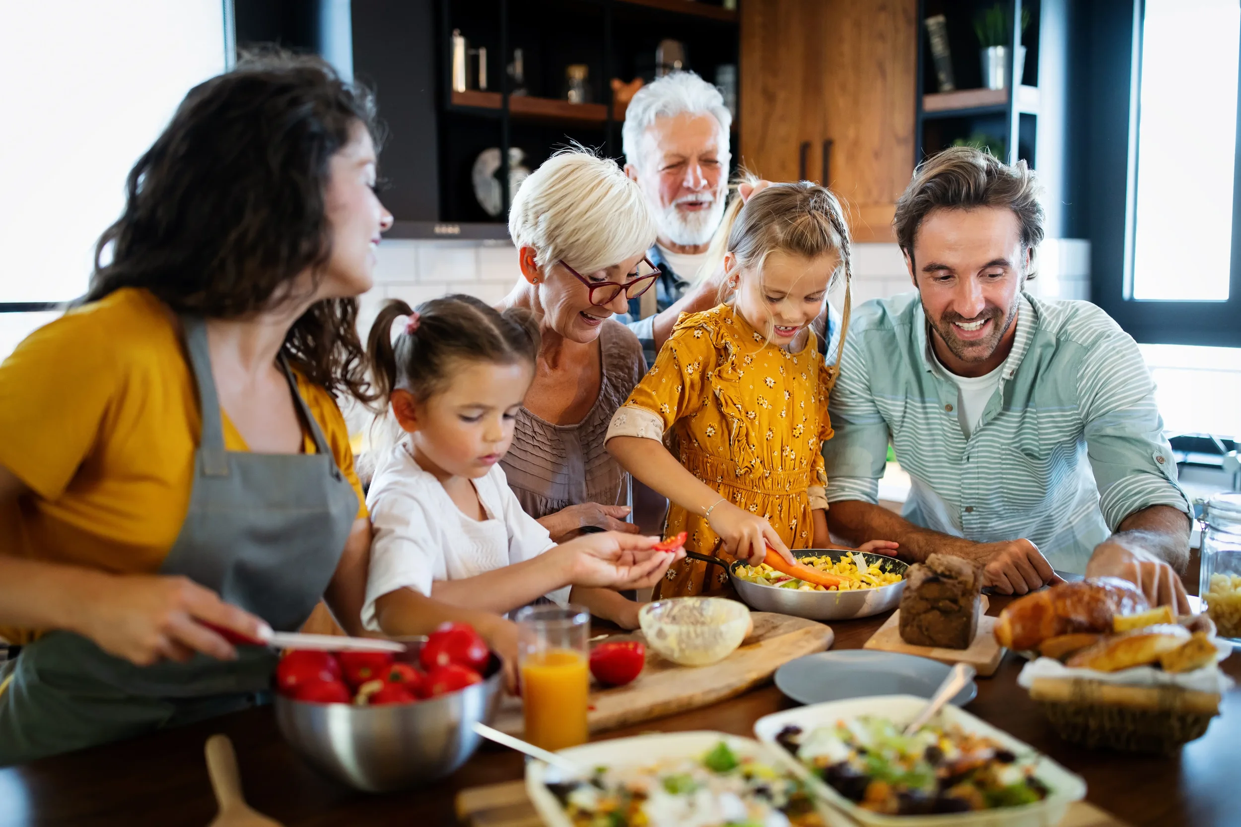 Grandparents, parents and children enjoying a meal together in the family kitchen.