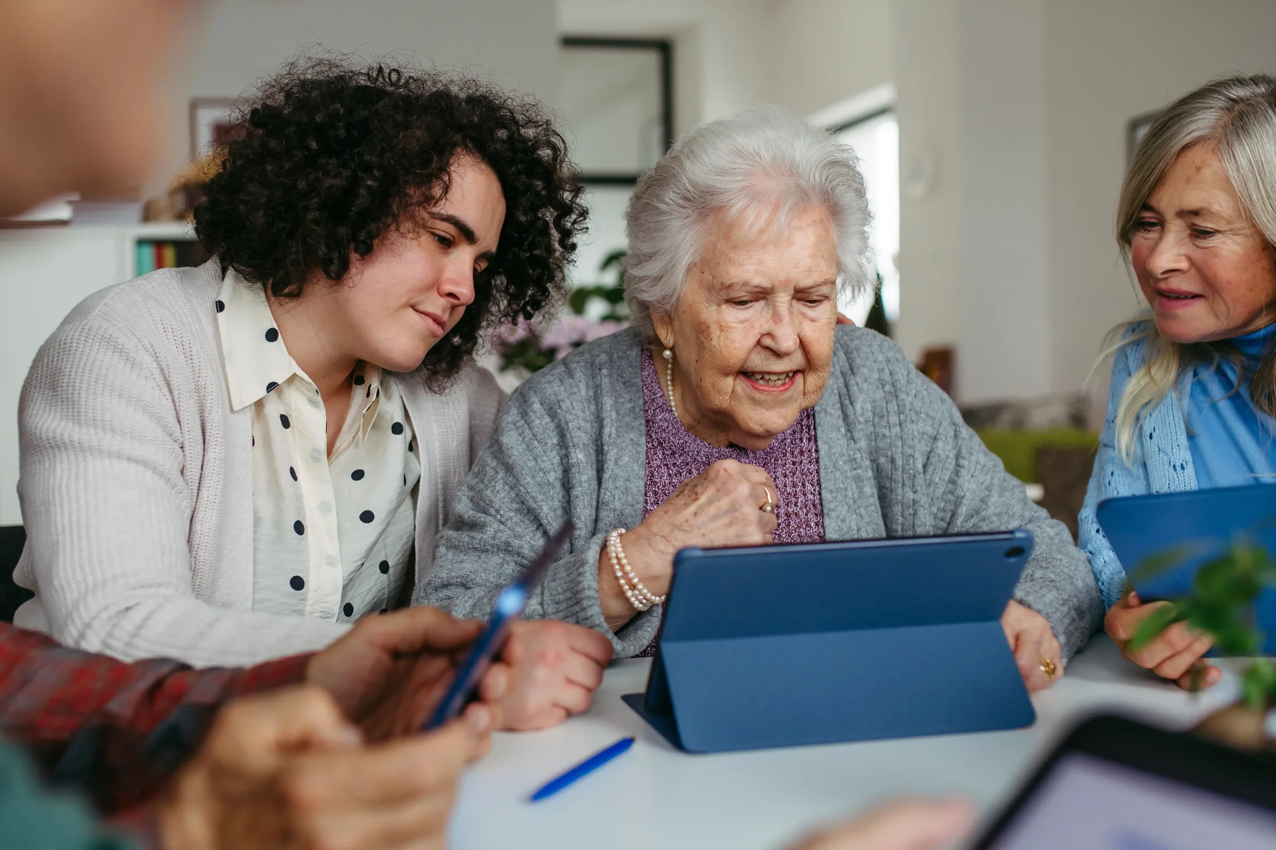 Three women from different generations looking concerned while reviewing information on a tablet device