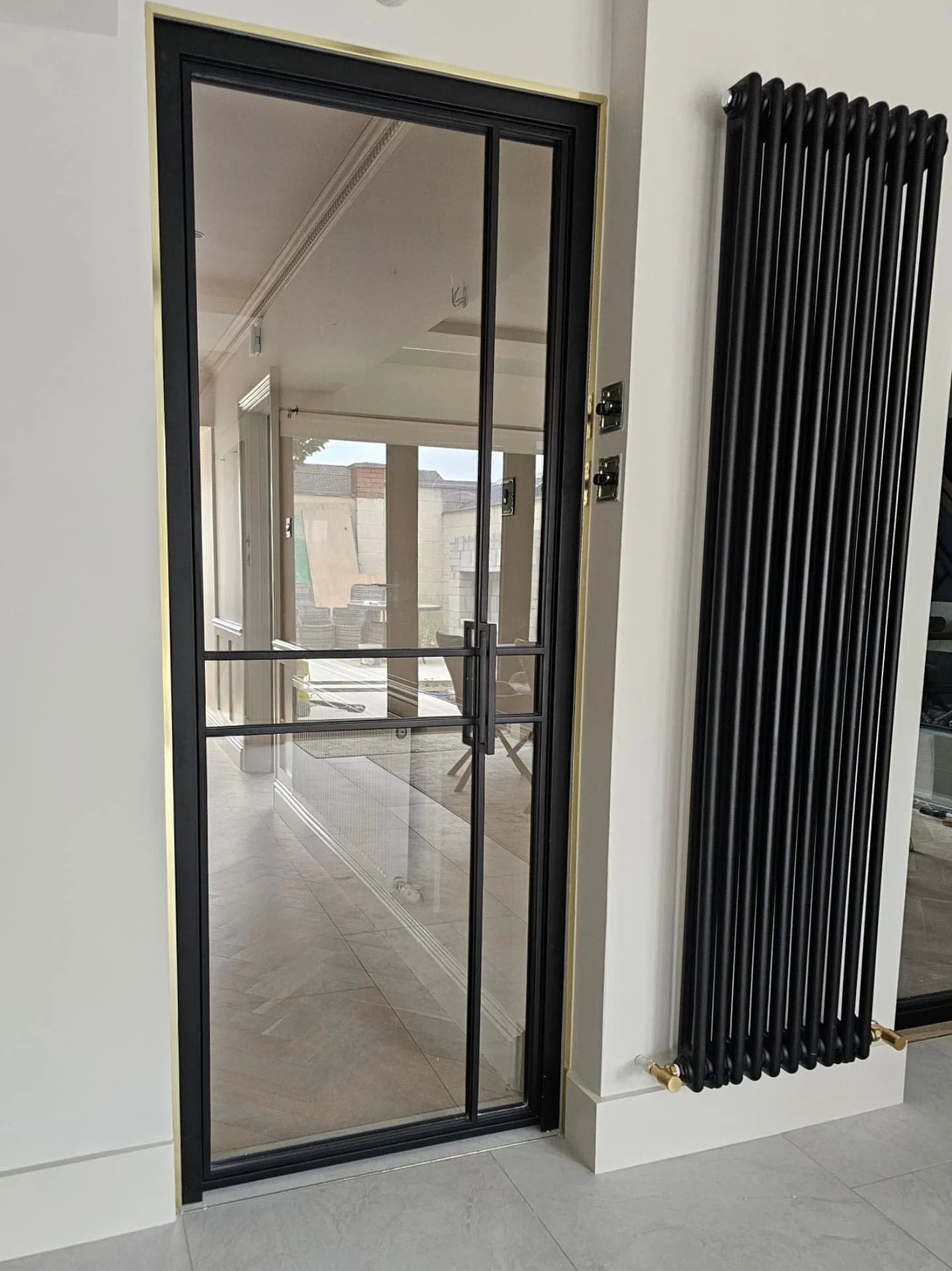 Recent install for a fresh renovation by Gallagh Homes.
The detailing on this project is next-level! Steel door, set neatly into a tiled opening, edged with fine gold trim which adds warmth against the monochrome scheme. Adjacent, a vertical colum r