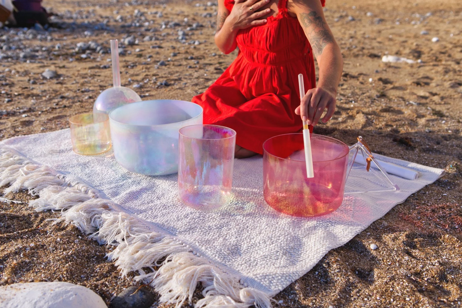Brighitta playing crystal singing bowls on a sandy beach at Seven Sisters, Eastbourne, Sussex.