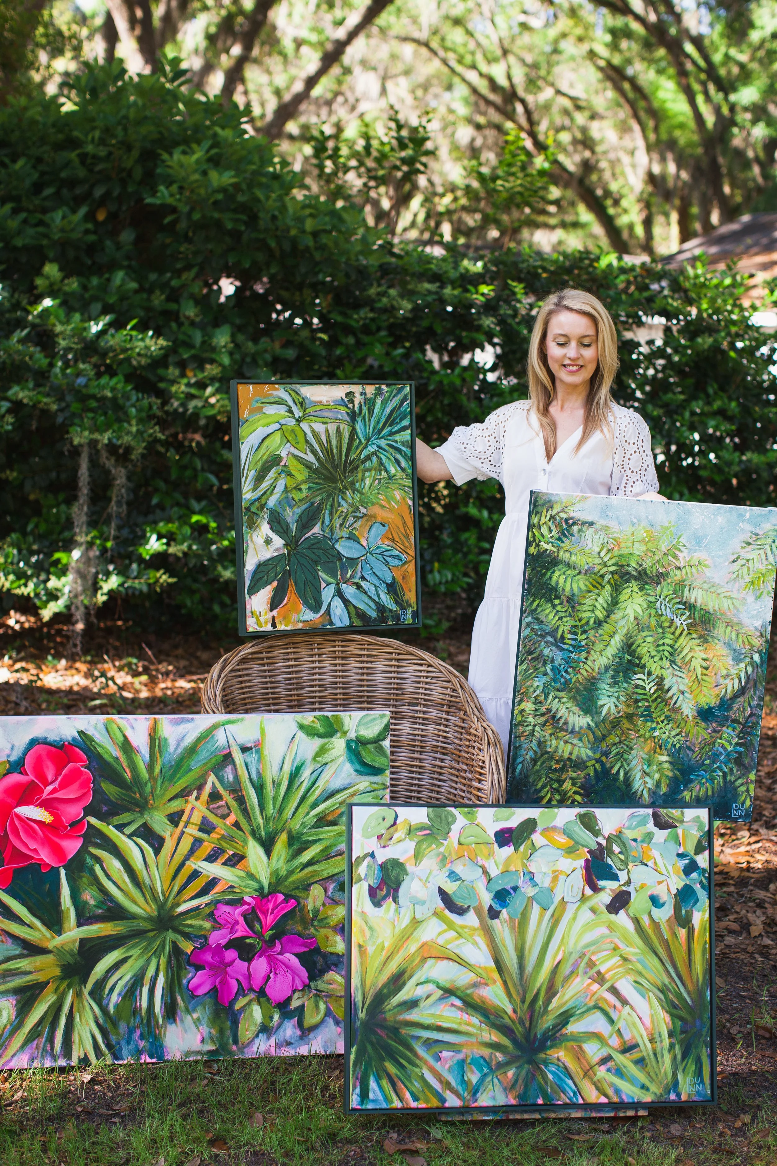 Artist outside with artwork and rattan chair
