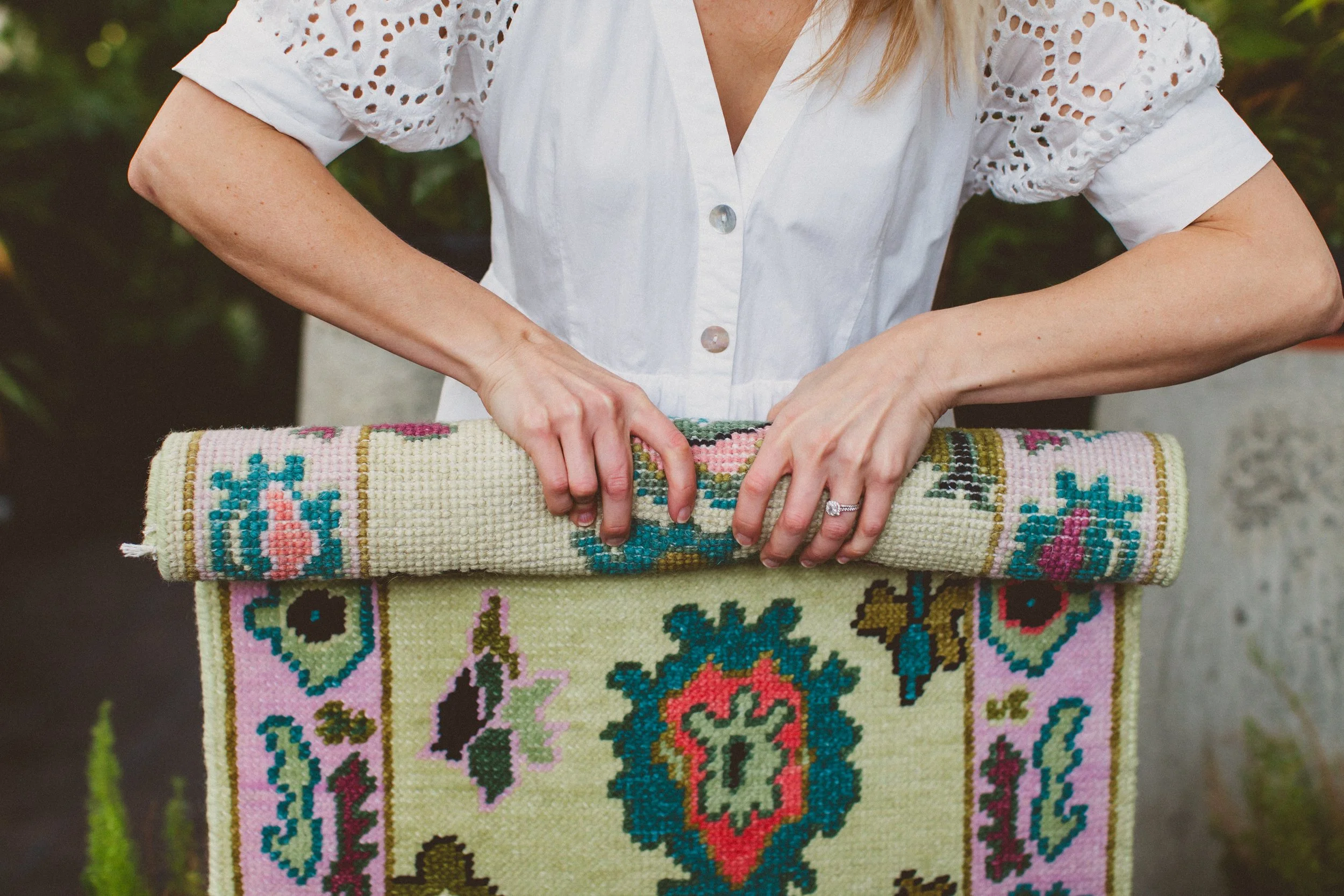 colorful oushak rug held by artist with plants