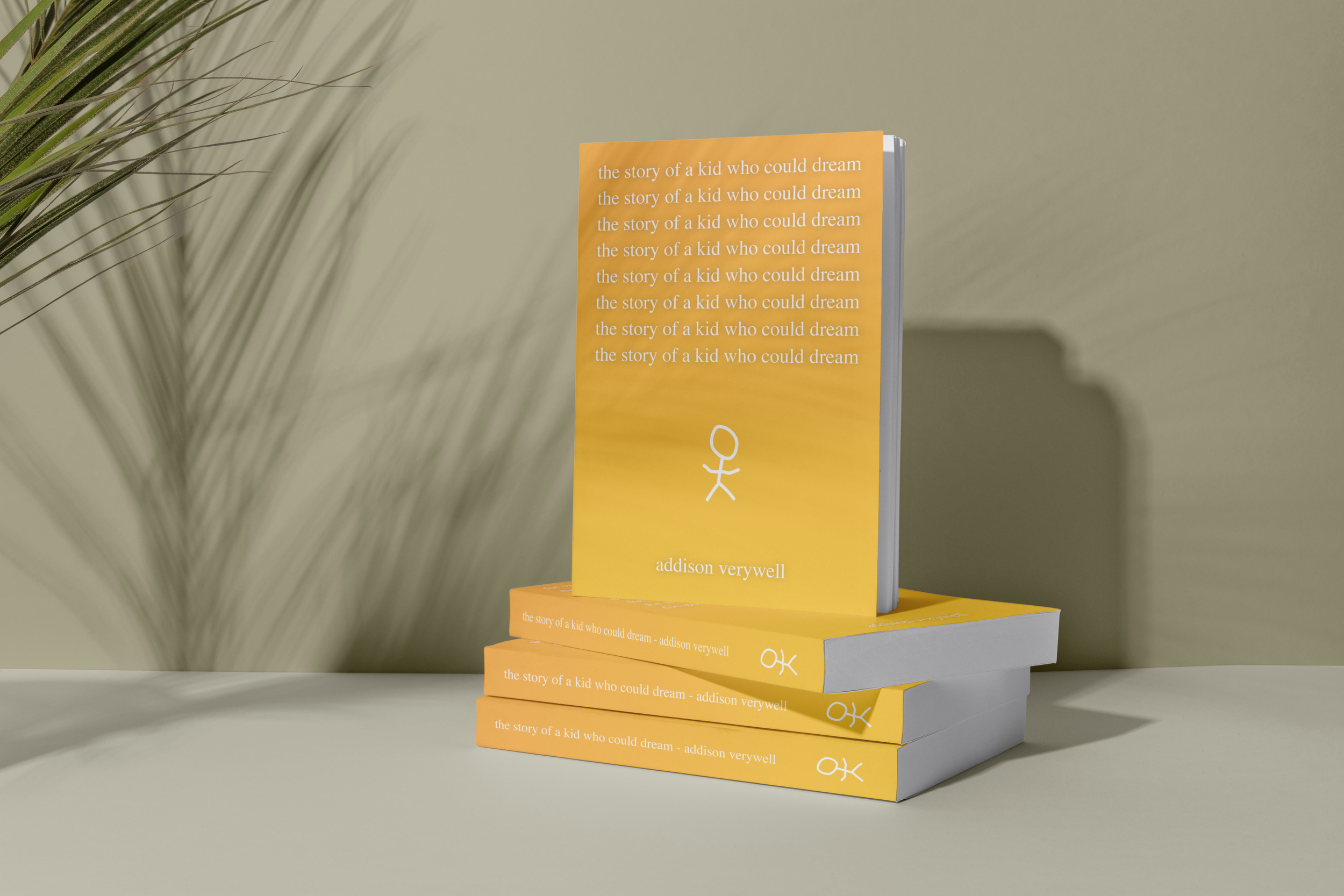 Four yellow books titled "The story of a kid who could dream" by Addison Verywell are stacked on a light-colored surface, with one book upright and the others lying flat. There is a large green plant on the left side of the image and a beige wall in 