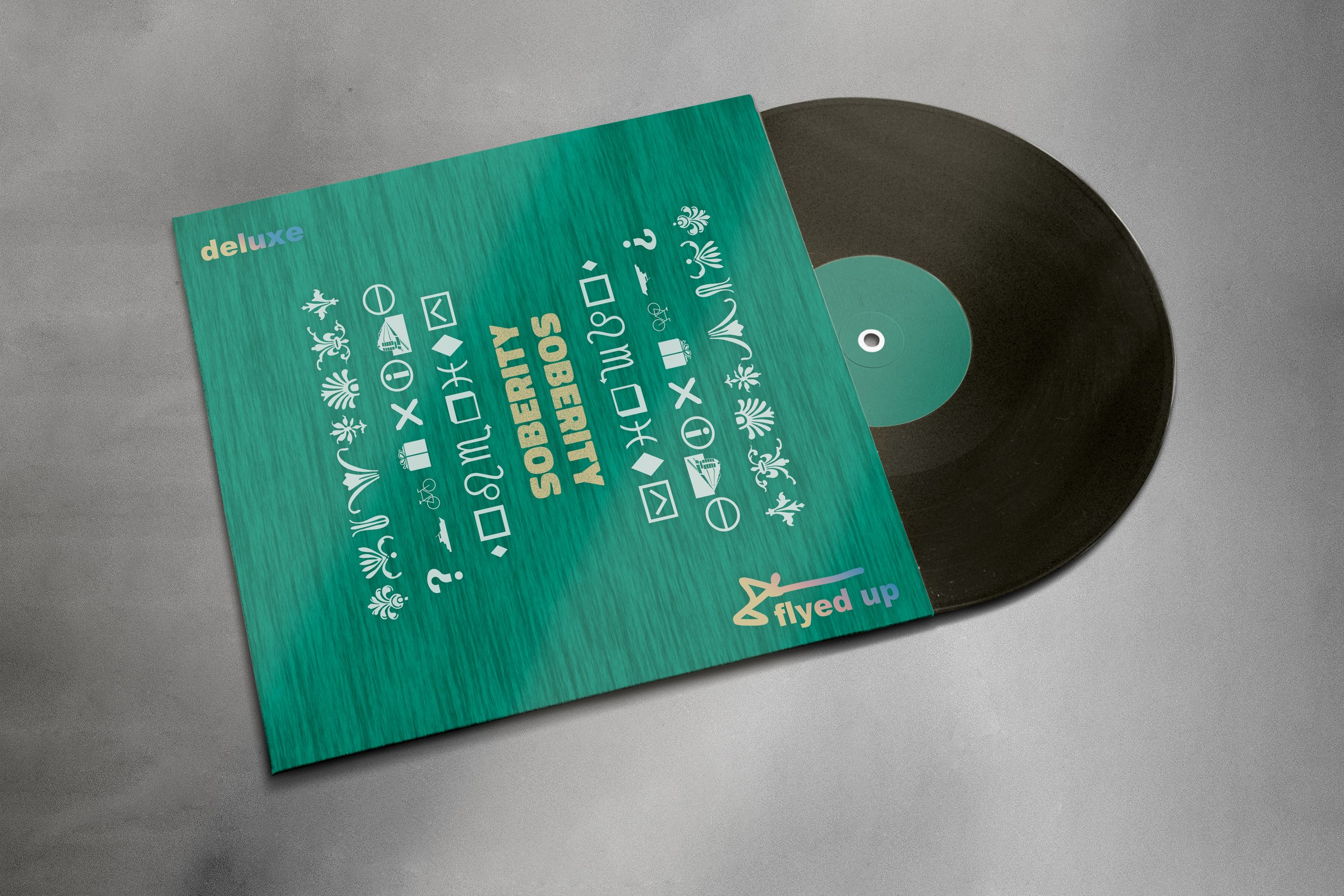 Vinyl record partially exposed next to a colorful, patterned album cover with text and symbols, on a gray surface.