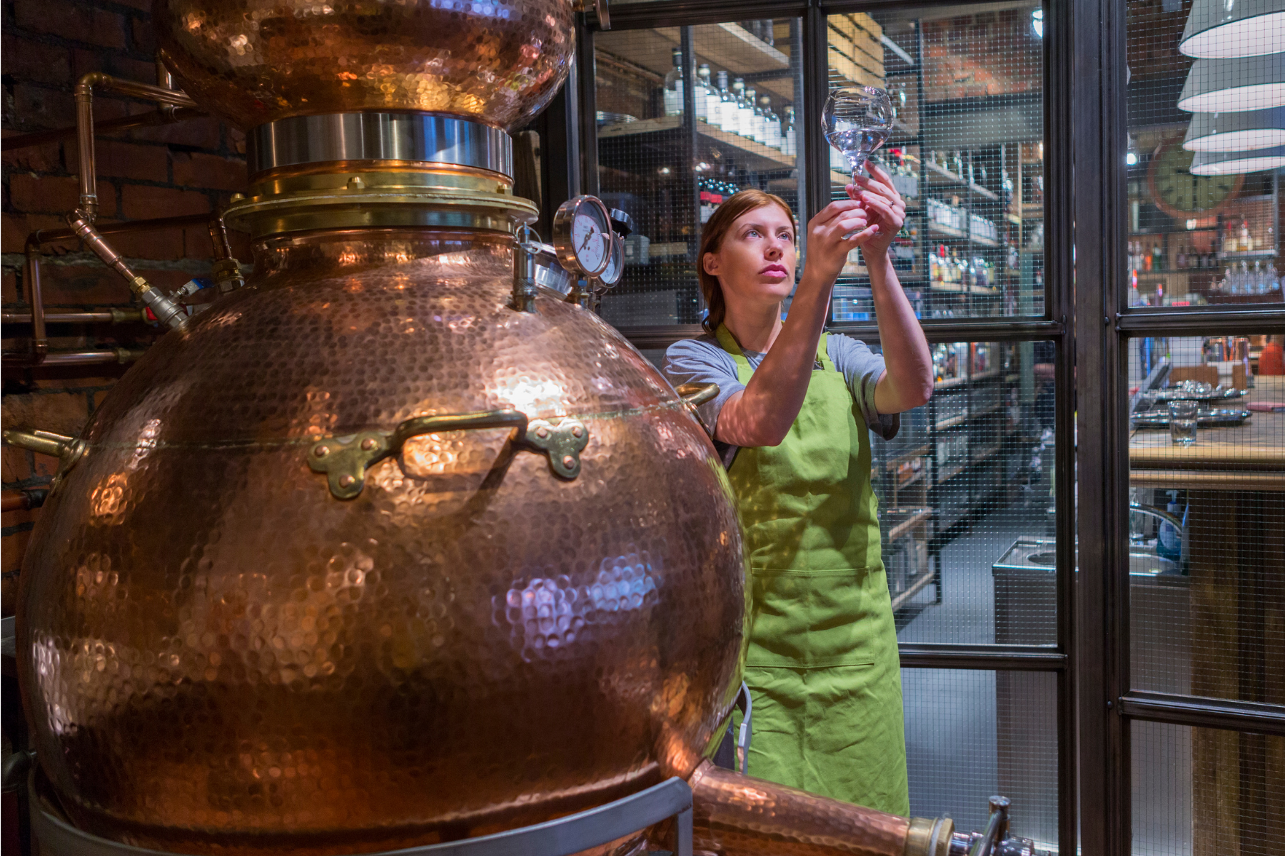 Woman holding a glass of moonshine at a distillery in the Shuswap