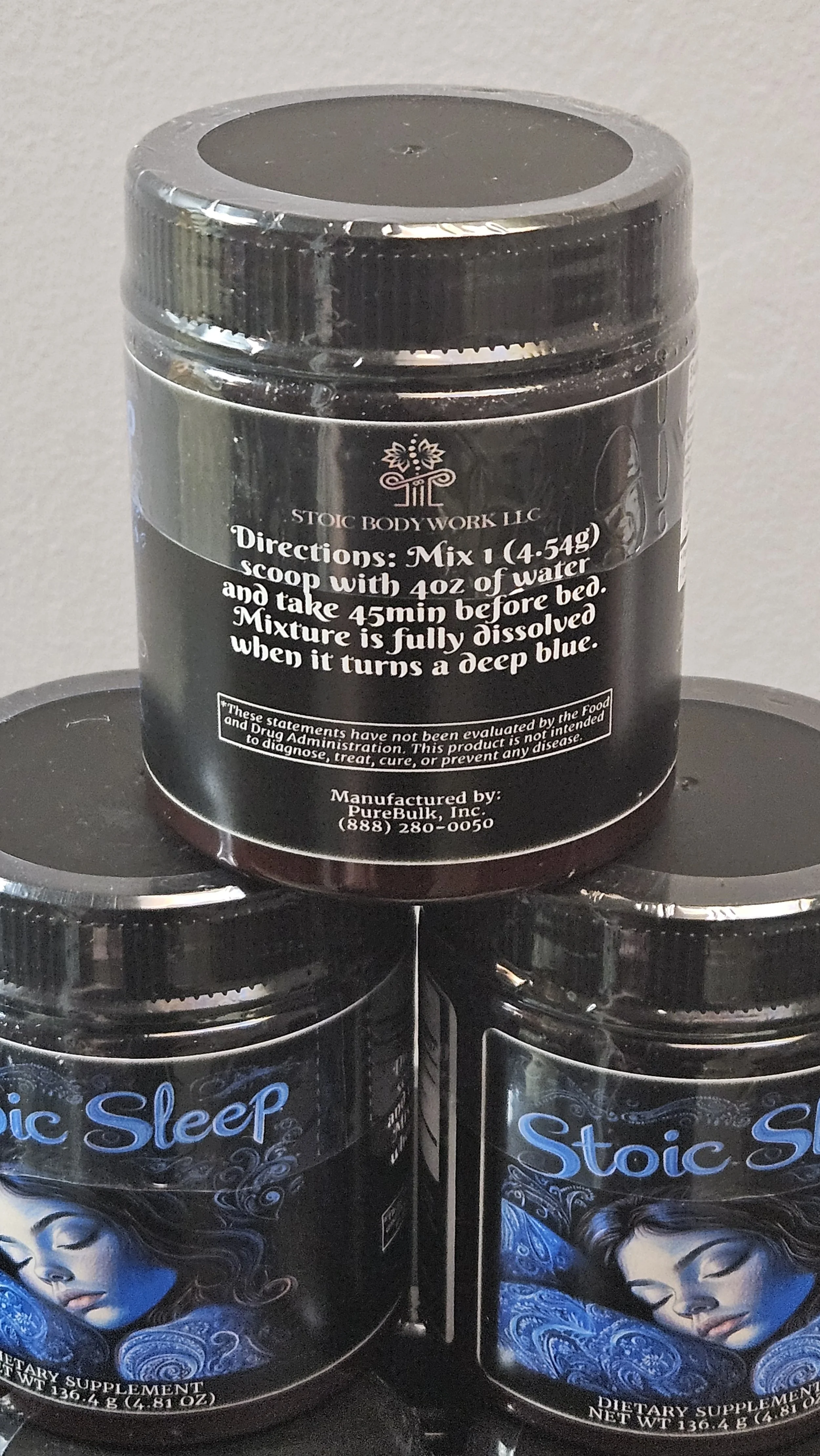 Container of Stoic Bodywork supplement with directions for use, placed on top of two other supplement containers called Stoic Sleep, showing a woman sleeping.