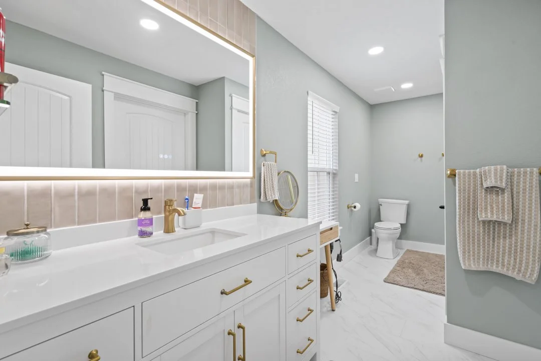 Luxury primary bathroom with custom cabinetry, quartz countertops, designer lighting, and upscale finishes in a custom-built Arkansas home.