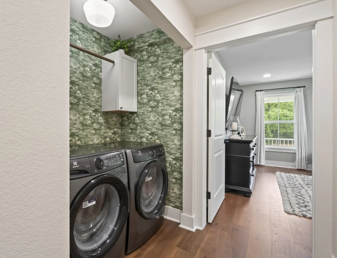 Custom home laundry room with built-in storage, designer wallpaper, and premium finishes in a custom-built home in Northwest Arkansas.