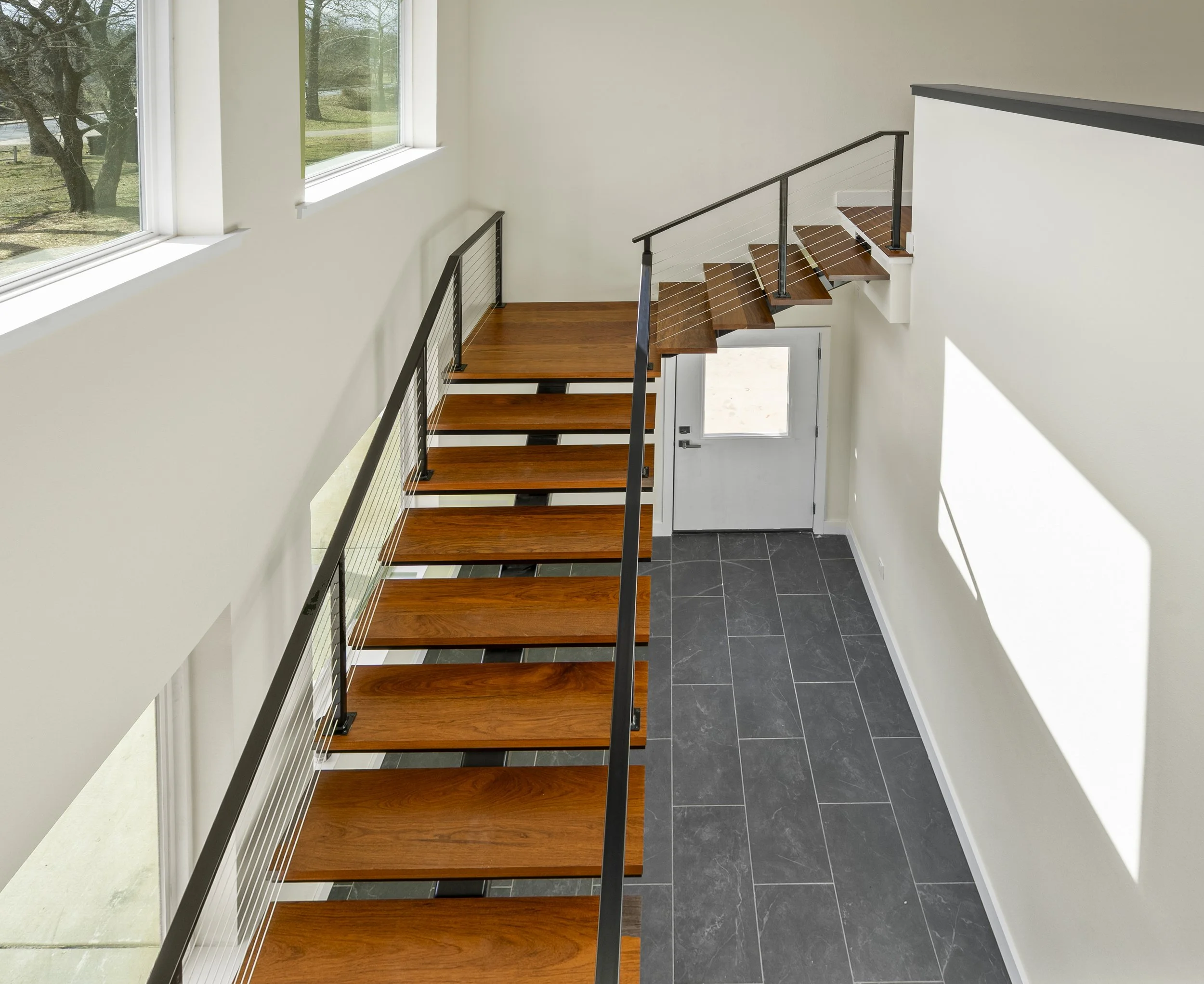 Custom home interior featuring modern wood staircase and tile flooring
