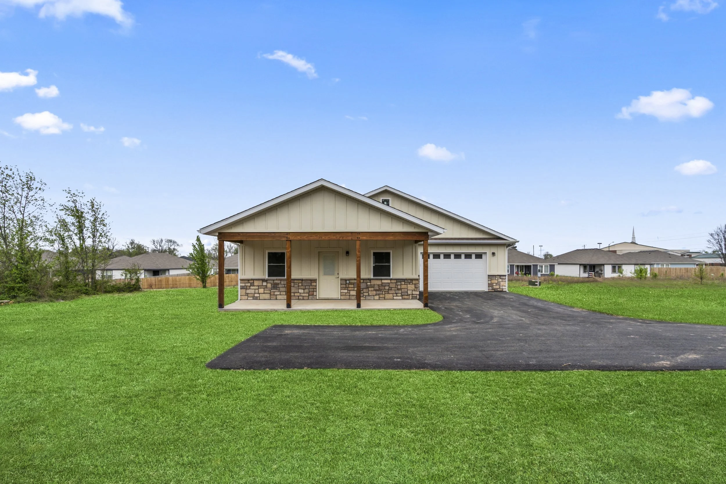 Modern single-story custom home with front porch and large yard in Northwest Arkansas