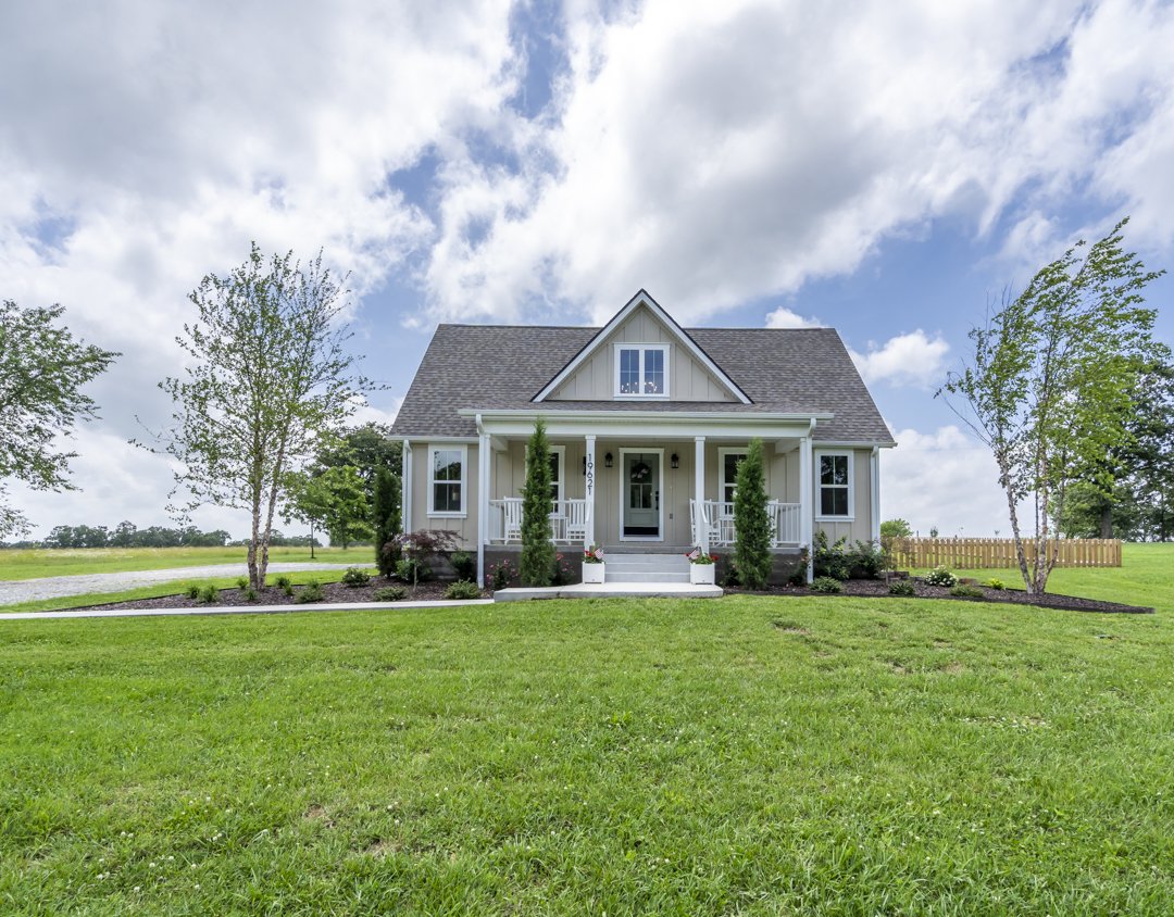 Custom farmhouse-style home built by a custom home builder in Siloam Springs, Arkansas, featuring a covered front porch, professional landscaping, and timeless curb appeal.
