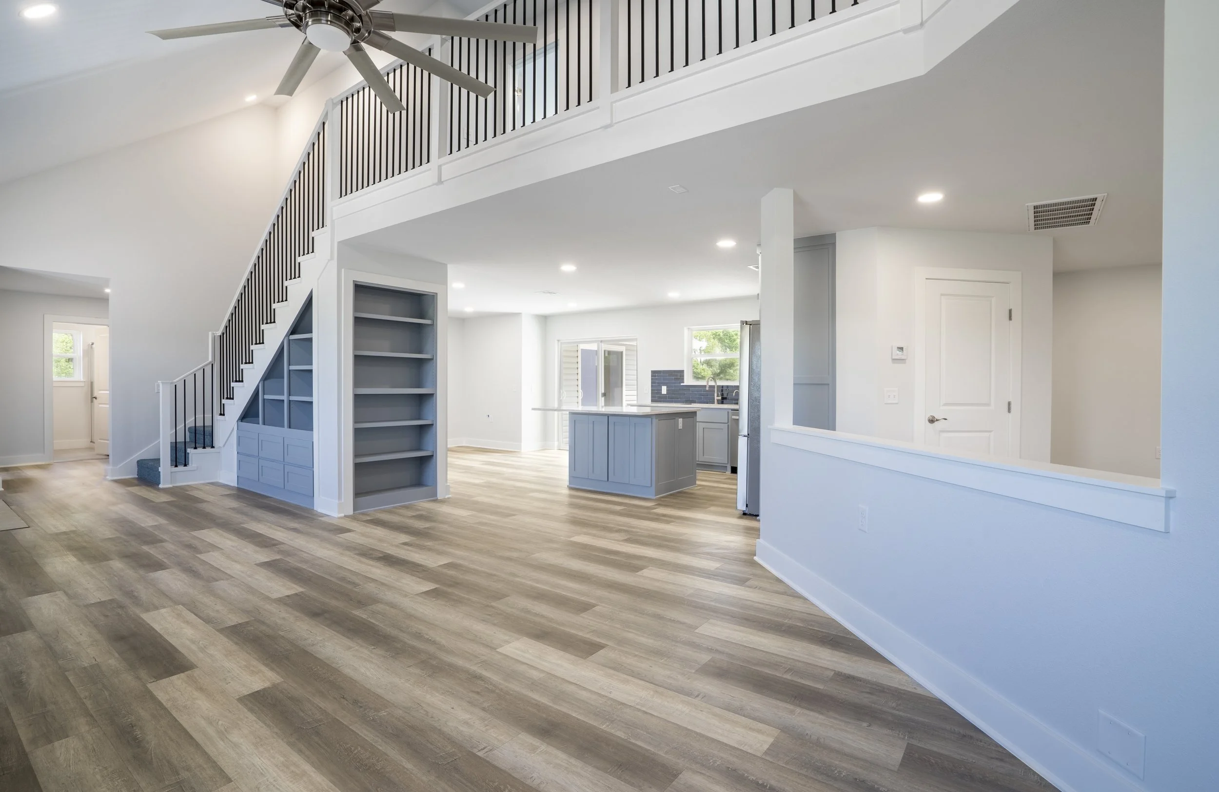 Open-concept custom home interior with staircase, built-in shelving, and modern kitchen built by Ahrenholtz Custom Homes in Northwest Arkansas