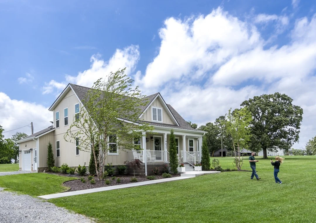 Custom farmhouse exterior with covered porch, oversized lot, and professionally designed landscaping built in Northwest Arkansas.