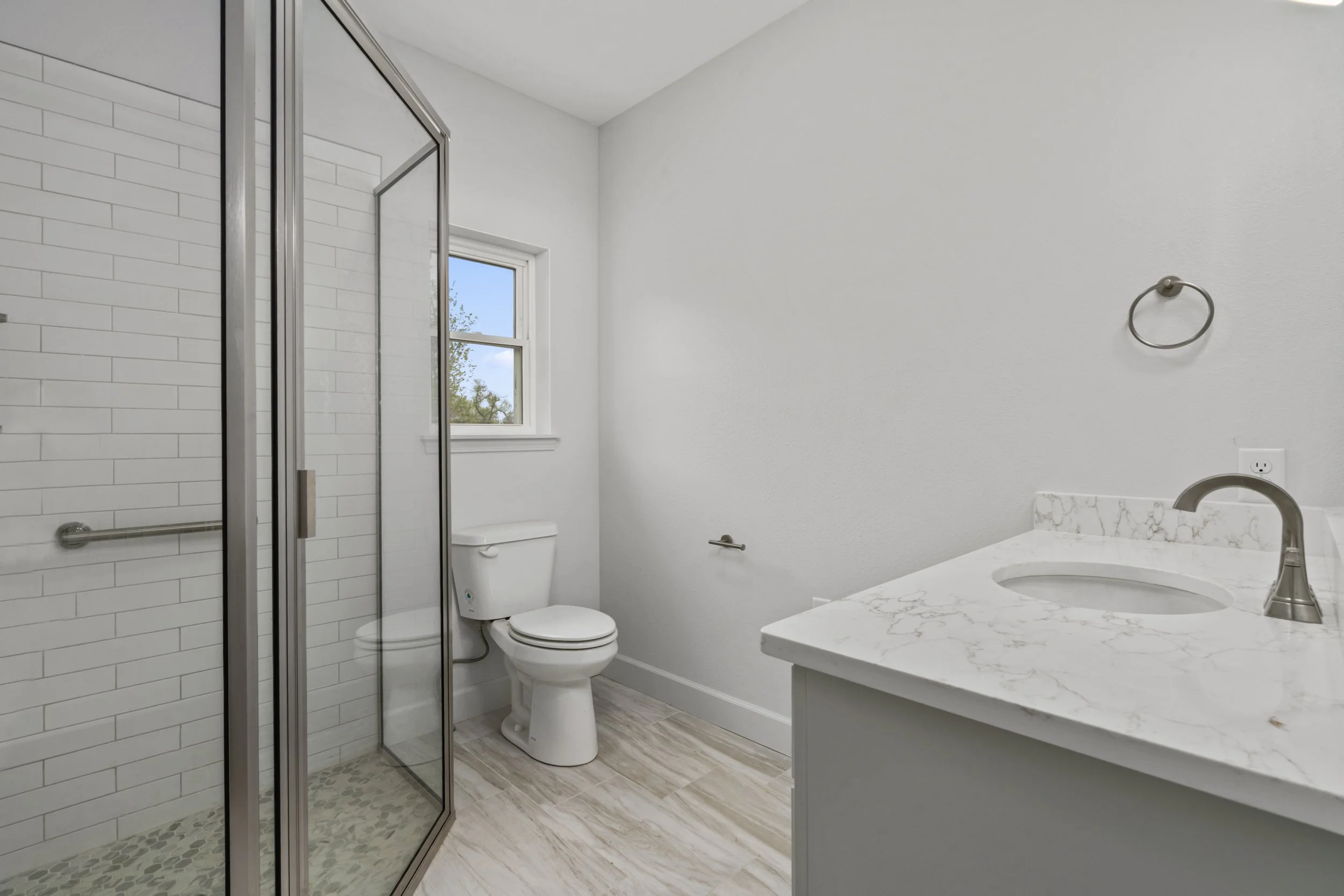 Modern bathroom interior featuring glass shower, marble countertop, and custom vanity