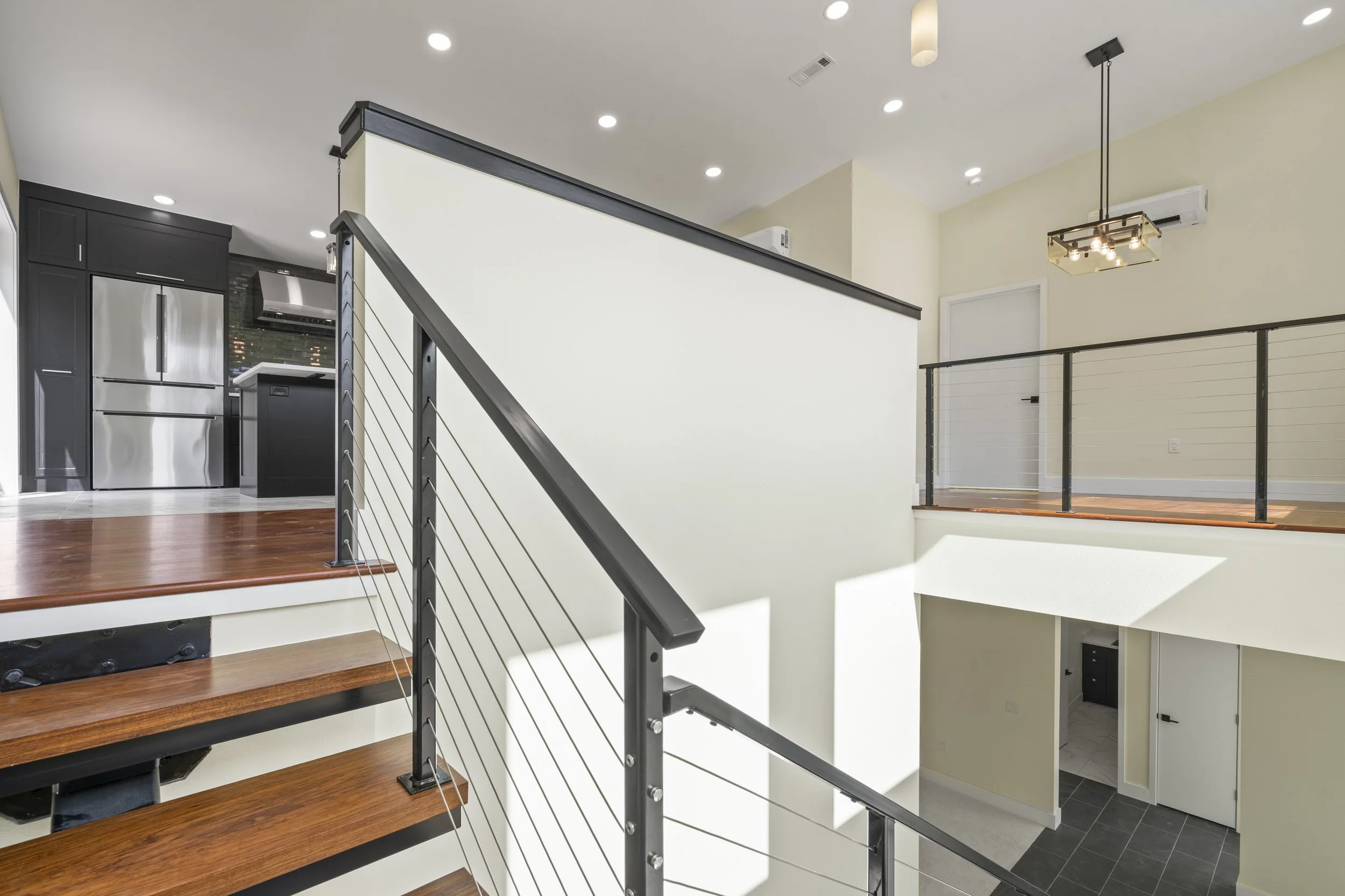 Modern custom home staircase with wood steps and cable railing built by Ahrenholtz Custom Homes in Northwest Arkansas