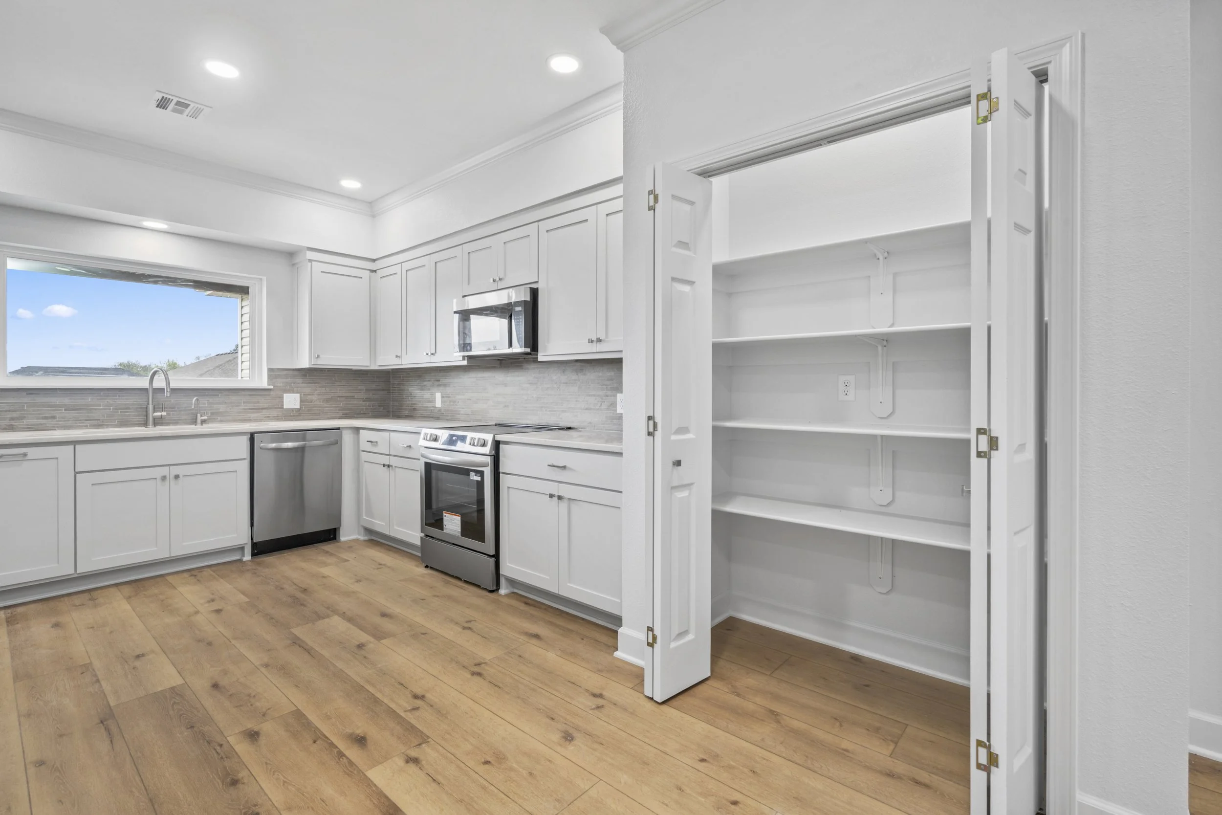 Open custom kitchen with pantry storage and modern finishes