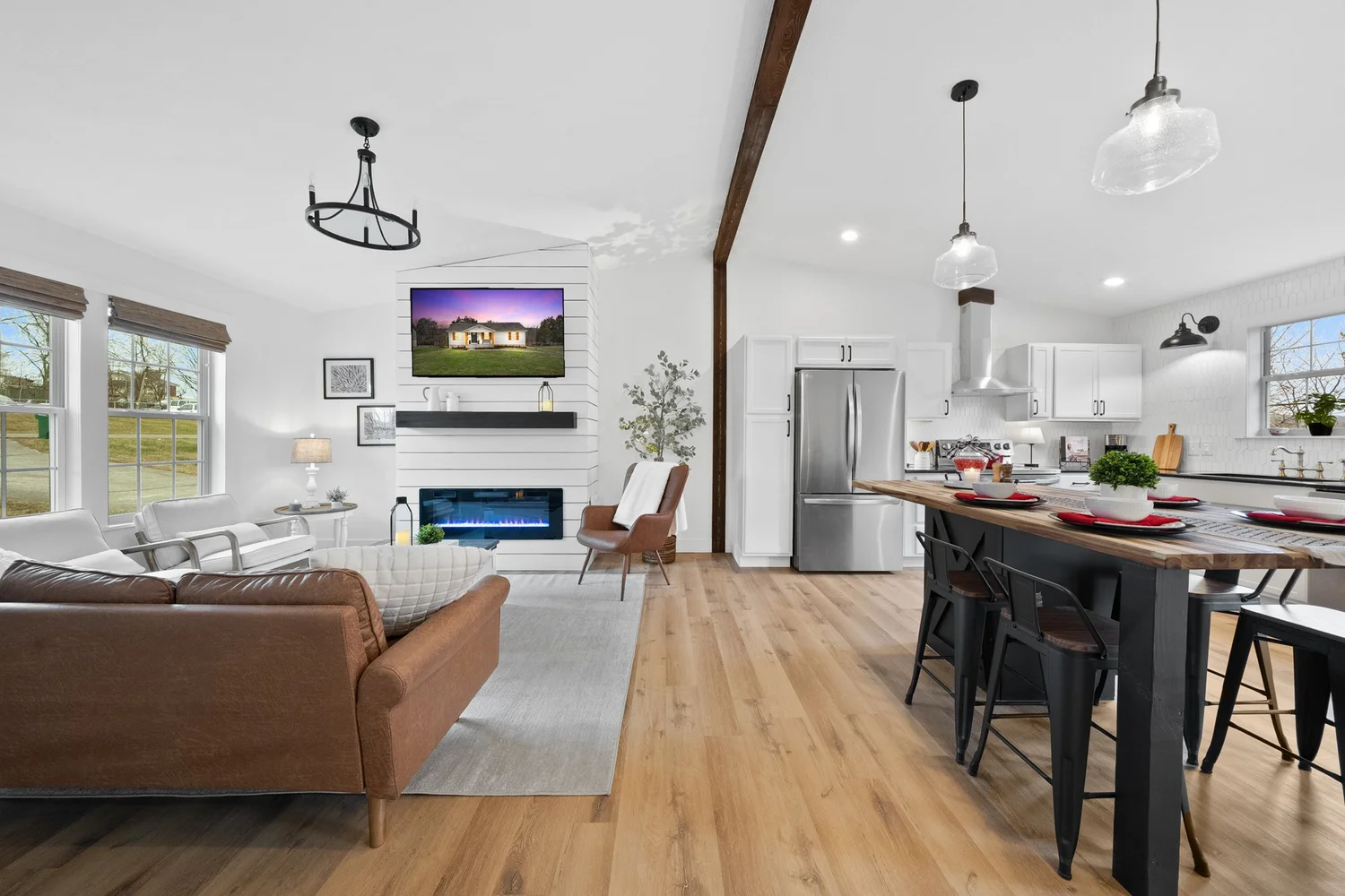 An open-plan kitchen, dining and living area with white walls and dark accents.