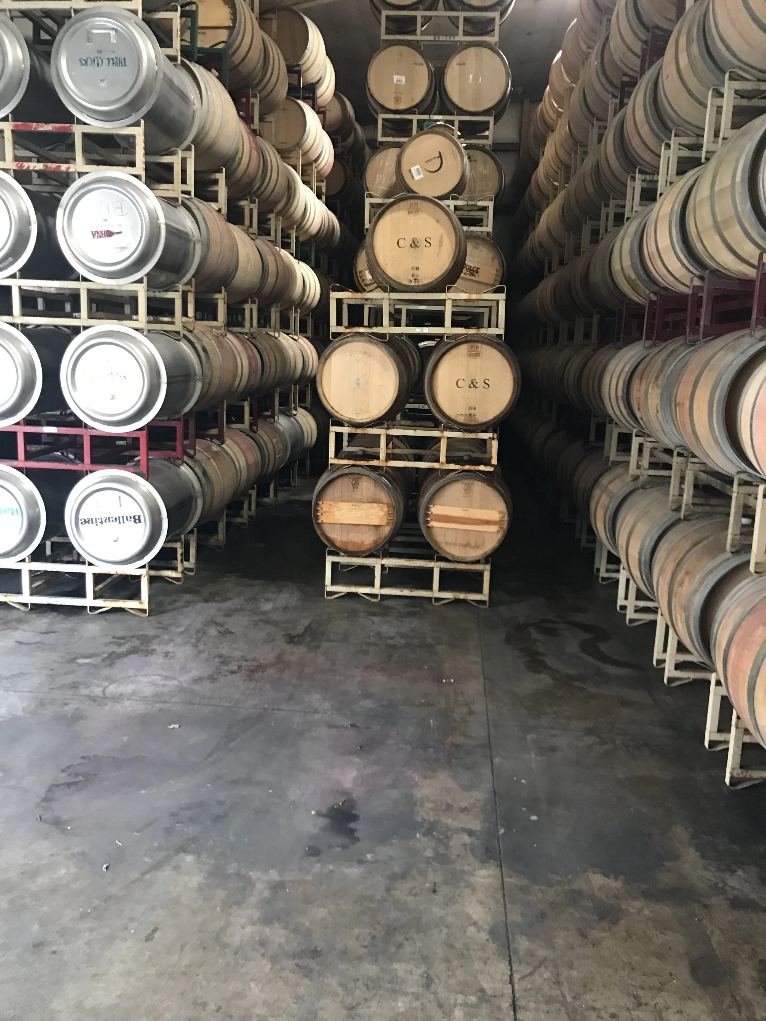 Rows of wine barrels stored on racks in a winery or cellar.