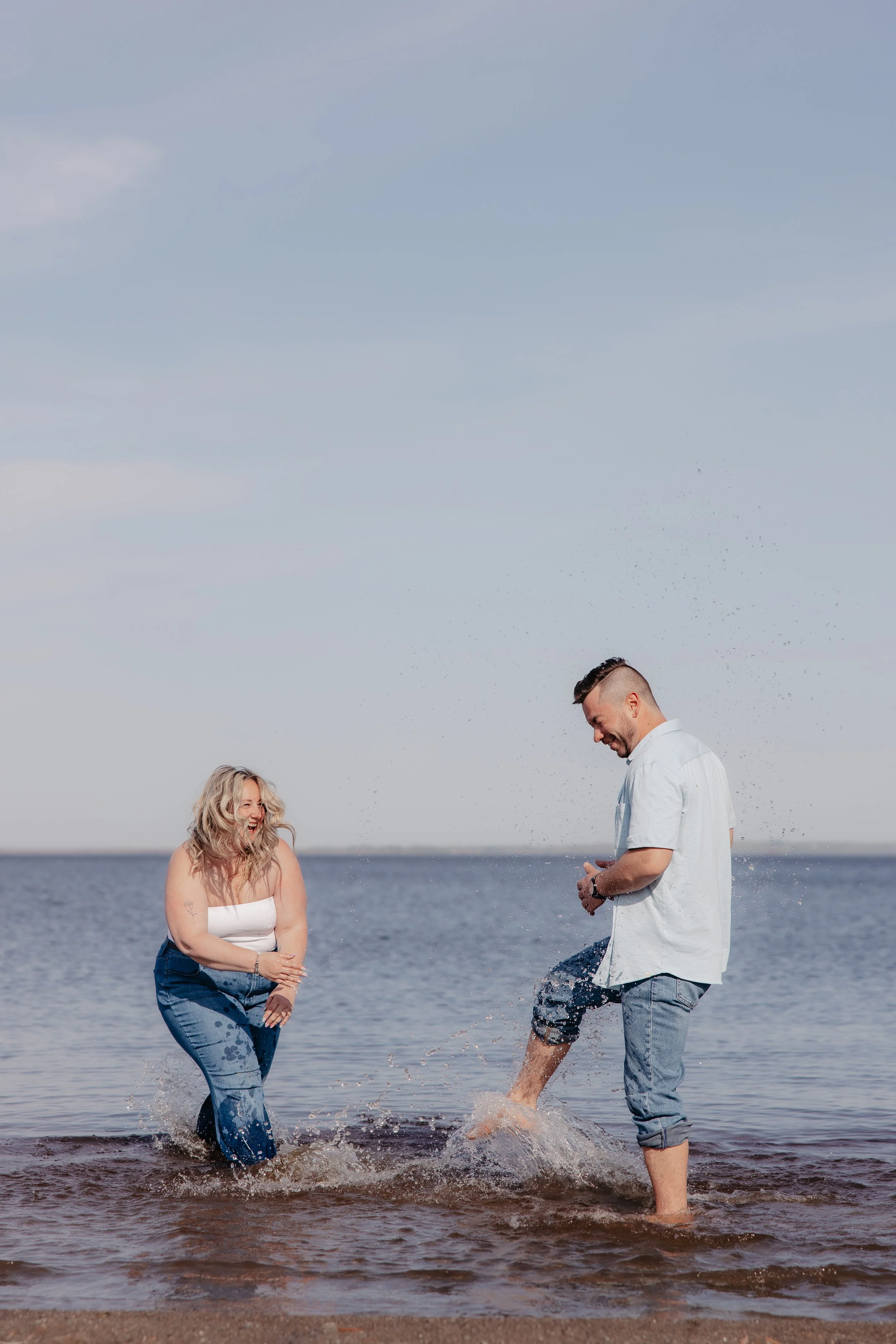 a couple playing in the water at the beach, laughing. Photo from a beach mini session in ottawa, photography